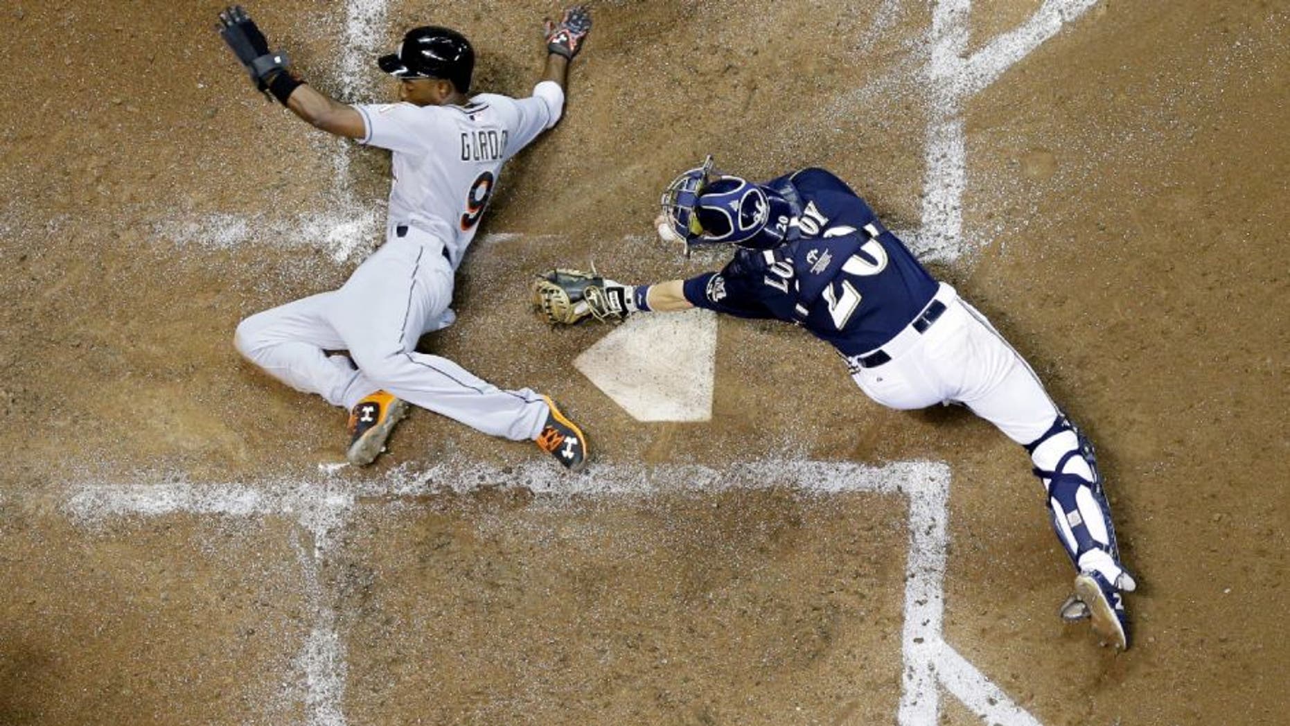 Miami Marlins' Dee Gordon slides safely past Milwaukee Brewers catcher Jonathan Lucroy during the fifth inning of a baseball game Monday, Aug. 17, 2015, in Milwaukee. Gordon scored from third on a sacrifice fly by Martin Prado. (AP Photo/Morry Gash)