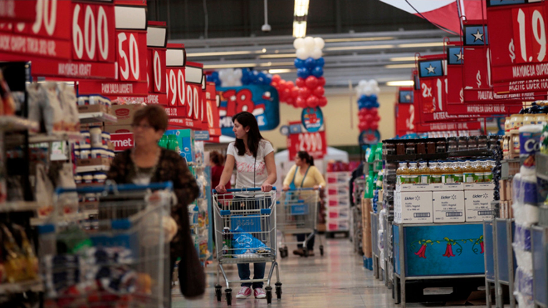 In this Sept. 1, 2015, photo, women shop in a Wal-Mart Lider hypermarket in Santiago, Chile. Soon after Wal-Mart's acquisition of the countrys largest supermarket chain Distribucion y Servicio, S.A., Wal-Mart made red the signature color for price signs for its Lider supercenters because Chileans associate red with good deals. (AP Photo/Luis Hidalgo)
