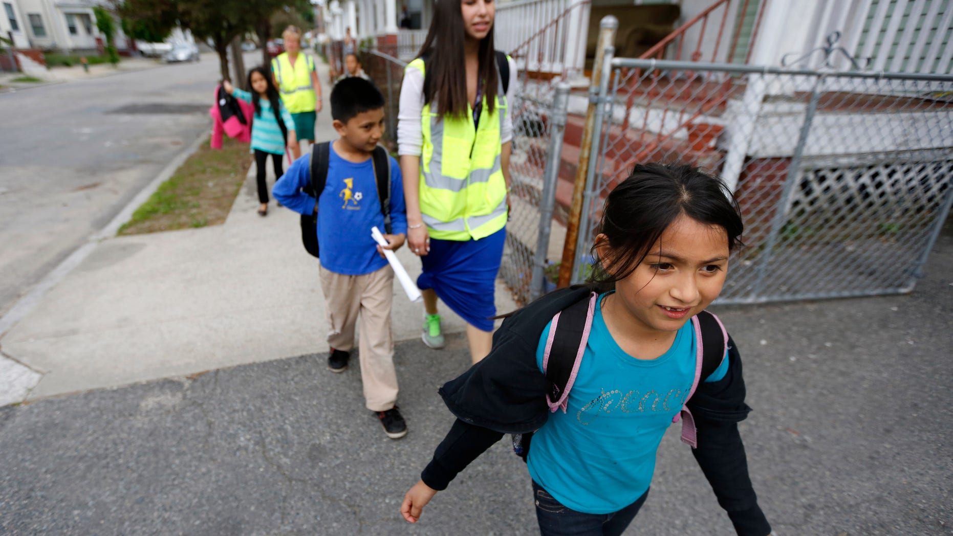 Divya Dahal, 8, walks home from school with a group of grade school children escorted by Allyson Trenteseaux, a Walking School Bus program manager, center right, in Providence, R.I. (AP Photo/Steven Senne)