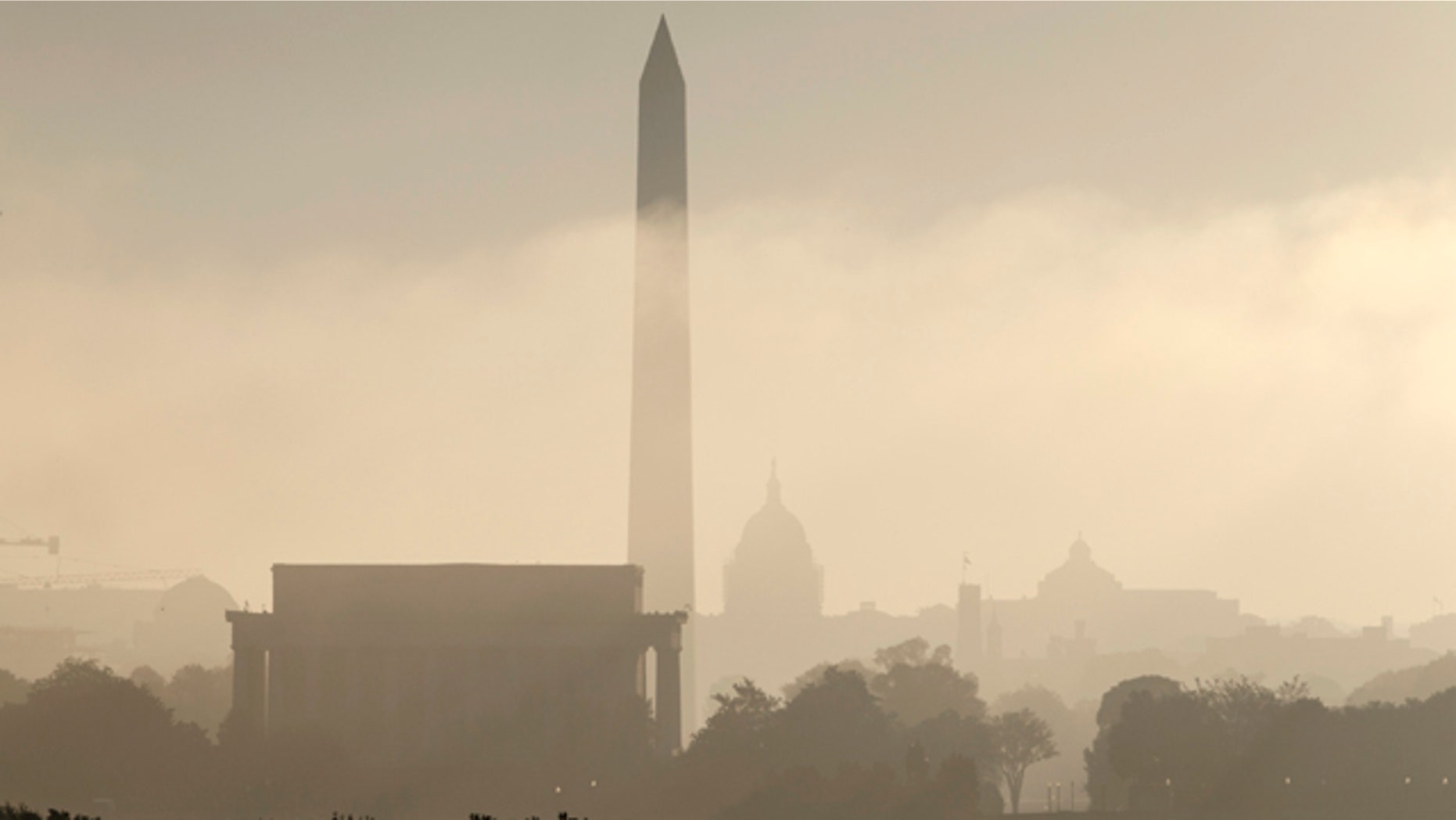 FILE- In this Sept. 26, 2014, photo, the monuments of Washington are silhouetted through the lifting fog over the nation's capitol as seen from an overlook in Arlington, Va. From left are, the Lincoln Memorial, Washington Monument, the Capitol, the Smithsonian Castle, and the Library of Congress. (AP Photo/J. Scott Applewhite, File)