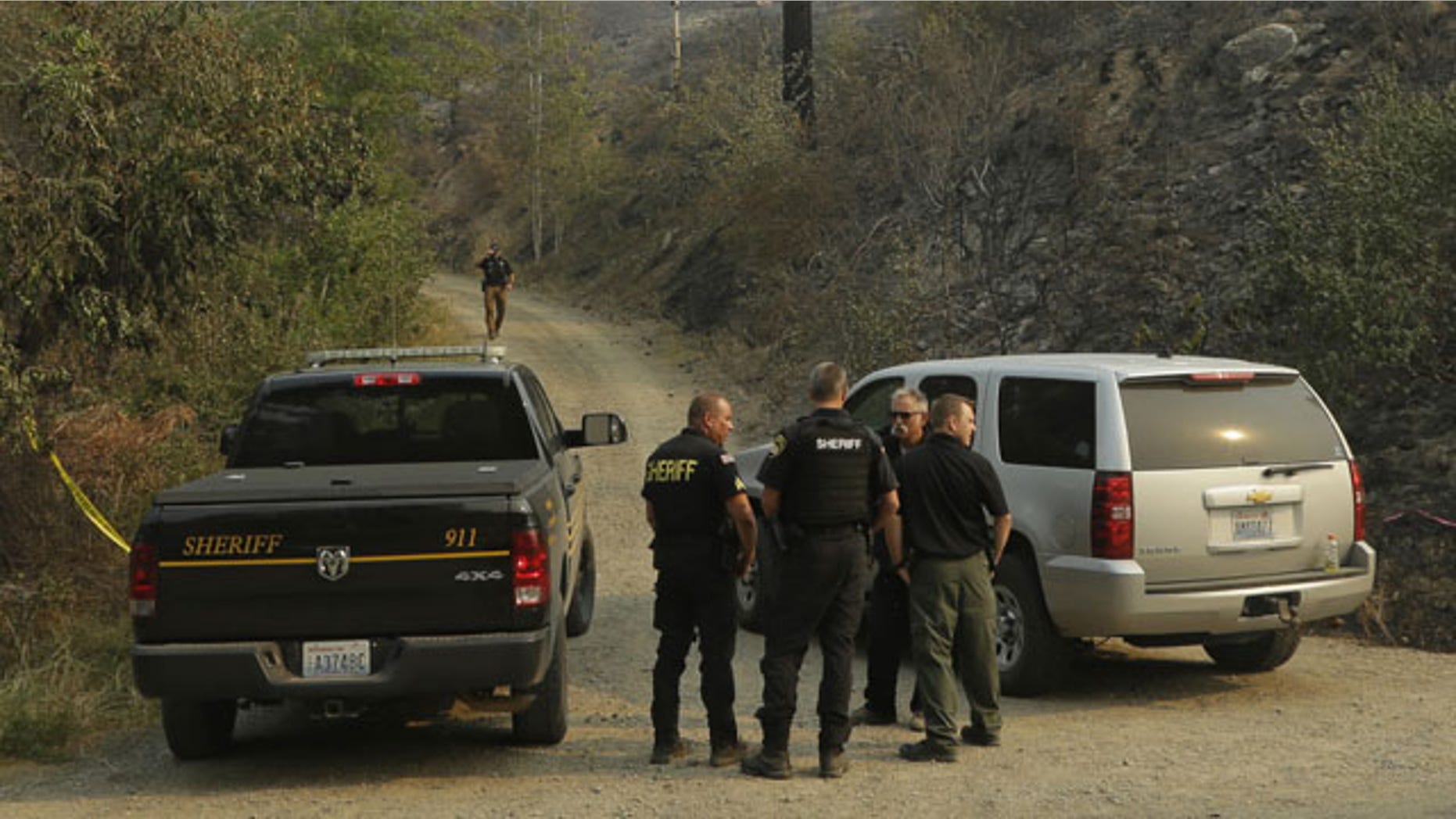 FILE - In this Thursday, Aug. 20, 2015, file photo, Okanogan County Sheriff's deputies guard the entrance to Woods Canyon Road near Twisp, Wash. (AP Photo/Ted S. Warren, File)