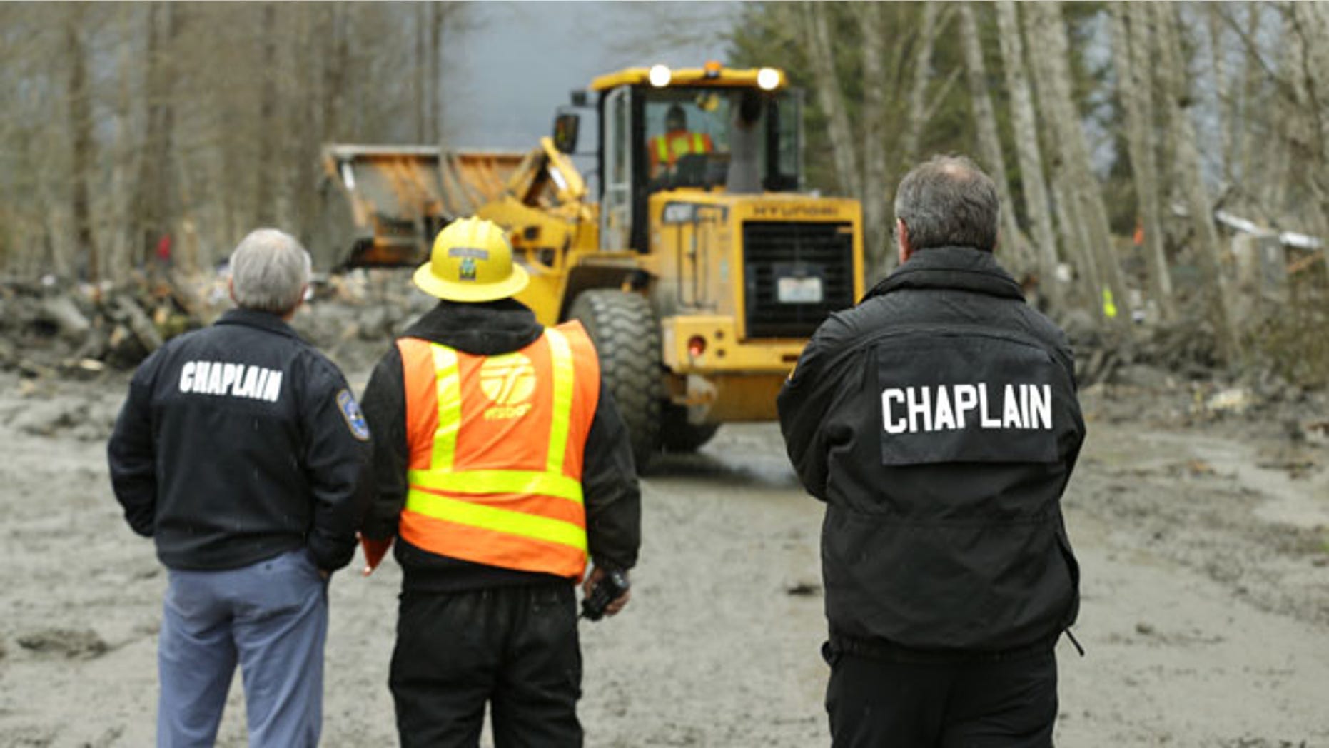 March 25, 2014: Washington State Patrol chaplains Joel Smith, left, and Mike Neil, right, watch as workers using heavy equipment work to clear debris from Washington Highway 530 on the western edge of the massive mudslide that struck near Arlington, Wash. Saturday, killing at least 16 people and leaving dozens missing. (AP Photo/Ted S. Warren, Pool)