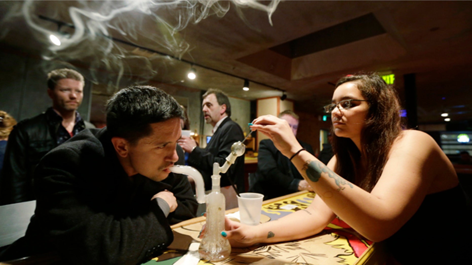 March 2, 2013: John Connelly, left, inhales marijuana vapor with the help of bar worker Jenae DeCampo, right, in the upstairs lounge area of Stonegate, a pizza-and-rum bar in Tacoma, Wash.