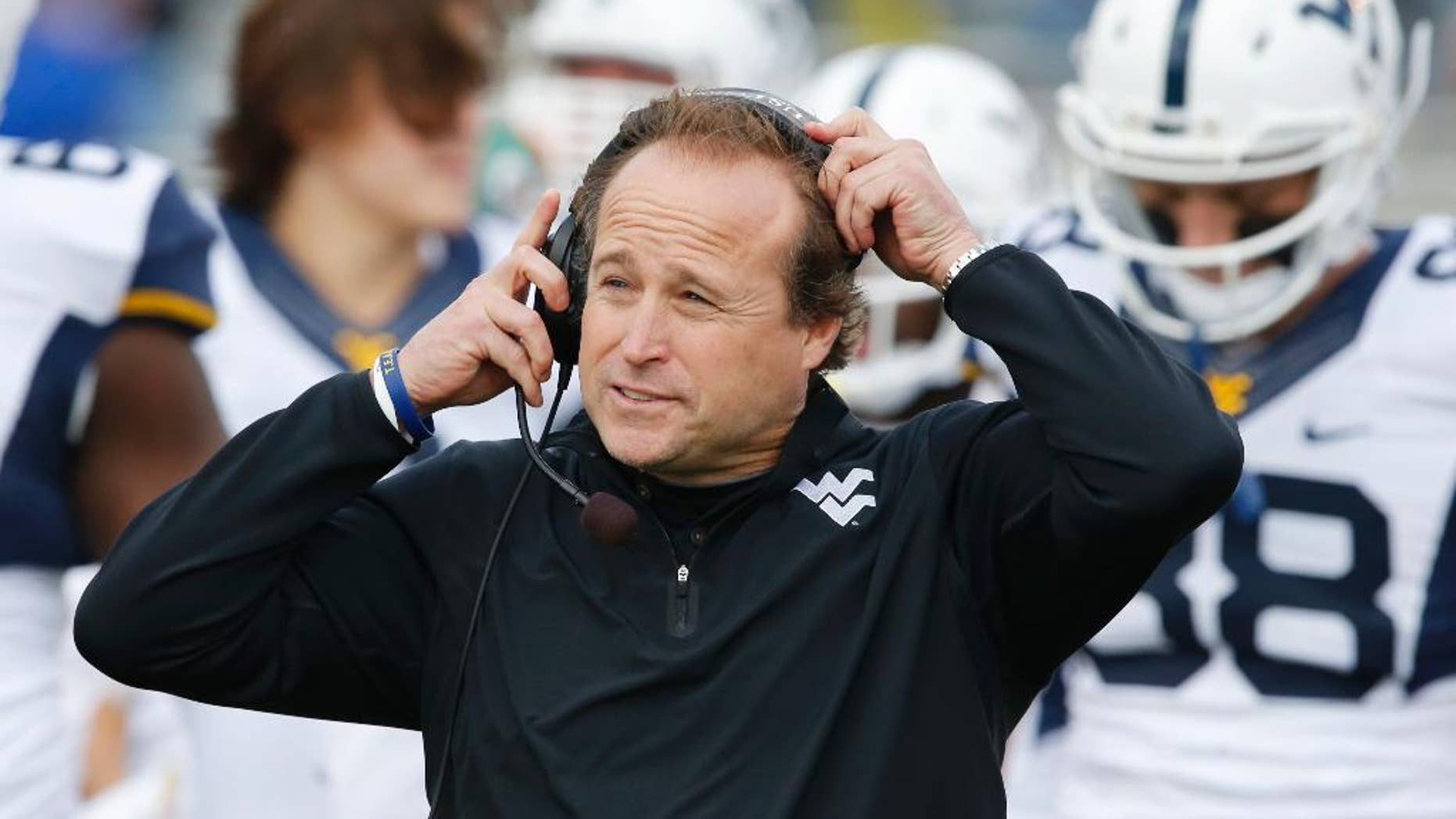 FILE - In this Nov. 16, 2013 file photo, West Virginia head coach Dana Holgorsen adjusts his headset during the first half of an NCAA college football game against Kansas at Kansas Memorial Stadium in Lawrence, Kan. The Mountaineers begin spring practice on Sunday, March 2, 2014, in Morgantown. (AP Photo/Orlin Wagner, File)