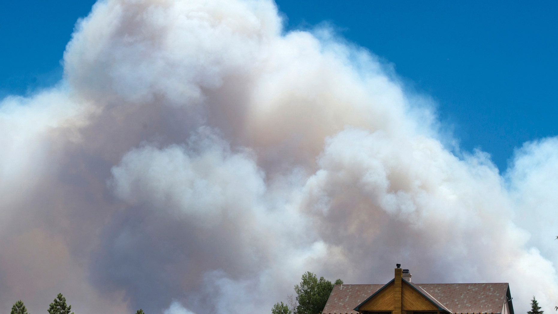 June 20, 2013: The smoke plume from the East Peak fire billows up behind a home on County Road 360 in La Veta, Colo.