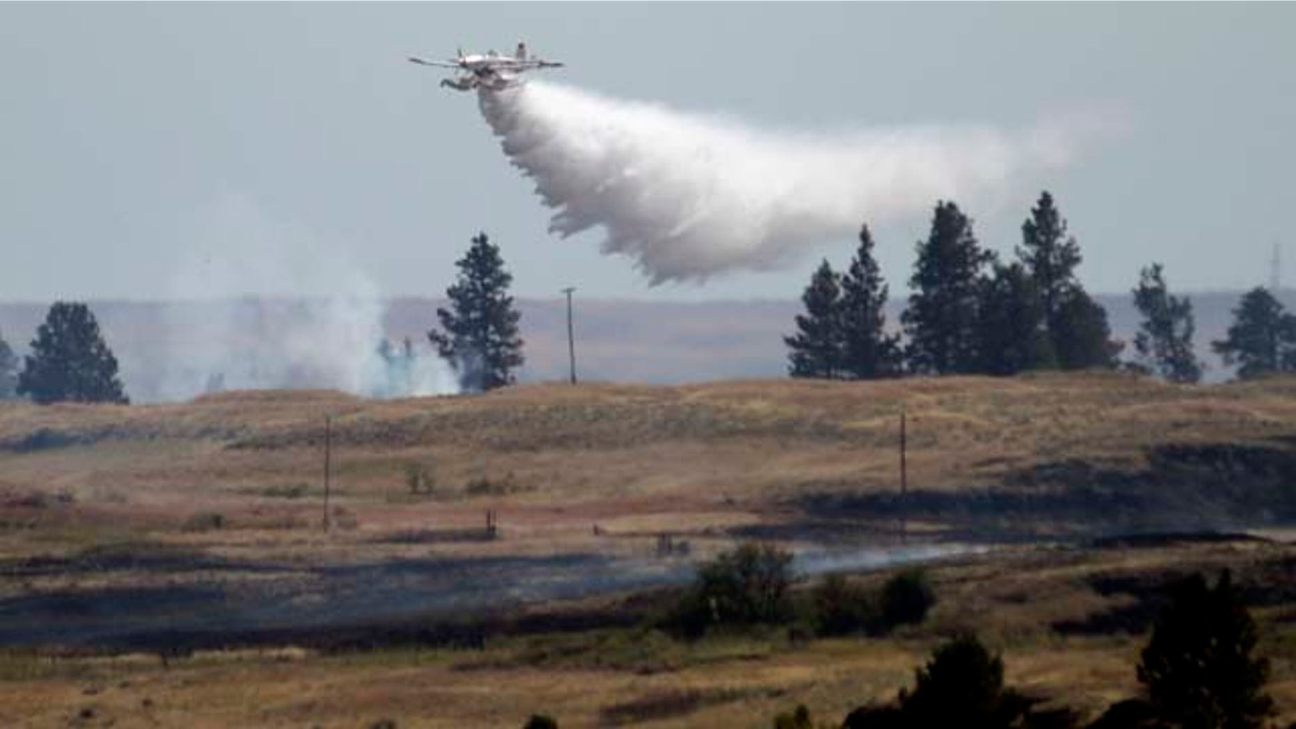 July 20, 2014: A firefighting plane drops water from Fishtrap Lake on a stubborn fire burning near the lake in Lincoln County near Cheney, Wash. (AP Photo/The Spokesman-Review, Jesse Tinsley)