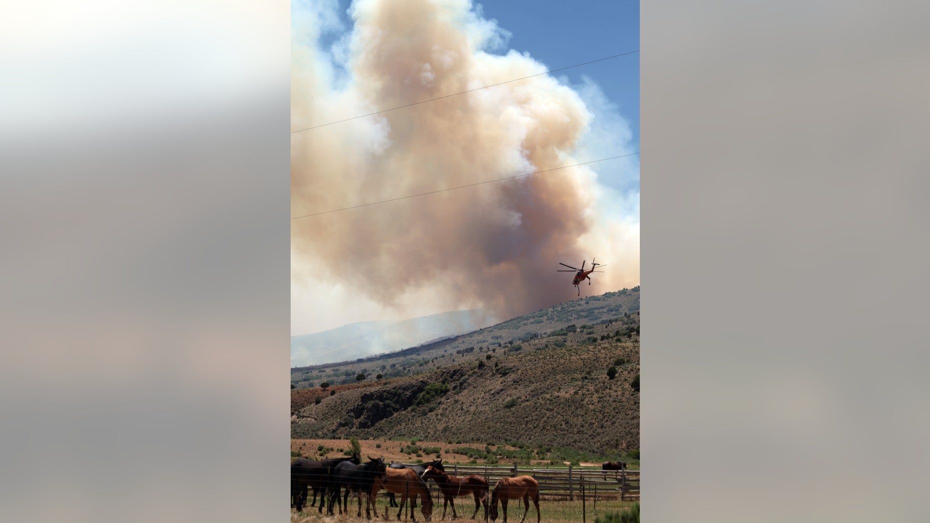 June 27- A helicopter carrying a bucket of water heads toward the Wood Hollow Fire in central Utah.