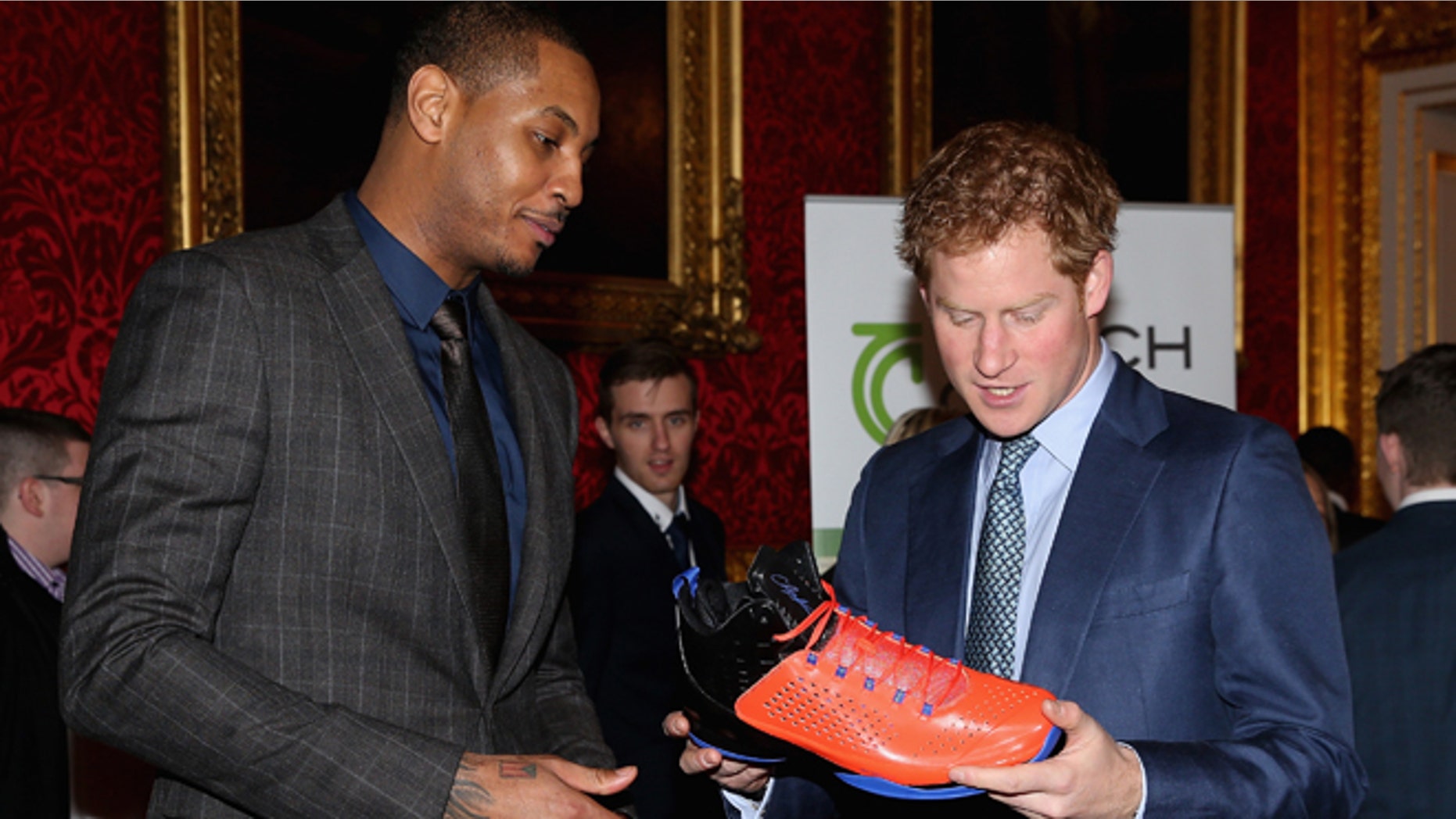 Britain's Prince Harry, right, is presented with a basketball shirt and size 15 basketball shoe by NBA All-Star Carmelo Anthony, during a Coach Core Graduation event at St James's Palace, in London, Wednesday, Jan. 14, 2015. The Coach Core model, a year's apprenticeship, aspires to produce well qualified sports coaches to work in the community. (AP Photo/ Chris Jackson, Pool)