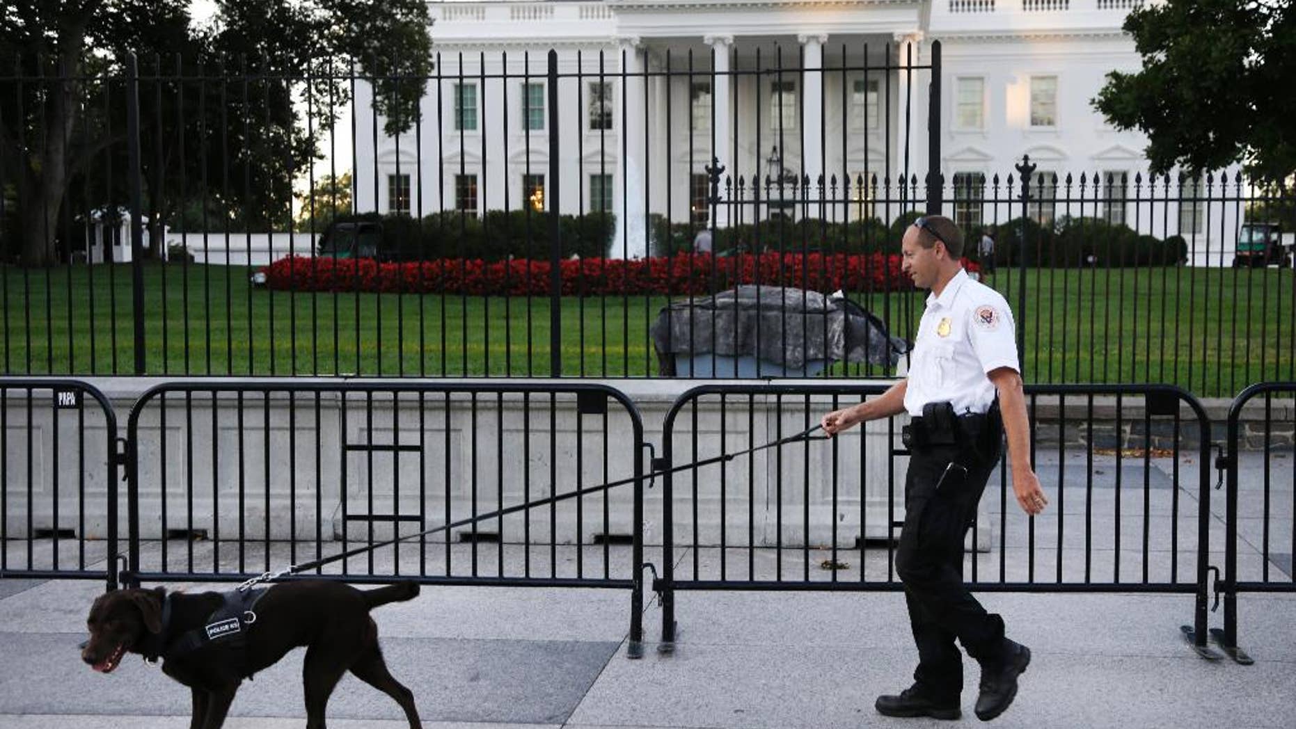 FILE - In this Sept. 22, 2014, file photo, a member of the Secret Service Uniformed Division with a K-9 walks along the perimeter fence along Pennsylvania Avenue outside the White House in Washington. Omar Gonzalez, 43, a knife-carrying Army veteran who scaled a White House fence and dashed into the executive mansion before being caught took a plea deal Friday, March 13, 2015. Gonzalez pleaded guilty to two federal charges. The Sept. 19 incident in which Gonzalez made it into the mansion's East Room preceded the disclosure of other serious Secret Service breaches in security for President Barack Obama and ultimately led to Julia Pierson's resignation as director of the agency. (AP Photo/Carolyn Kaster, File)