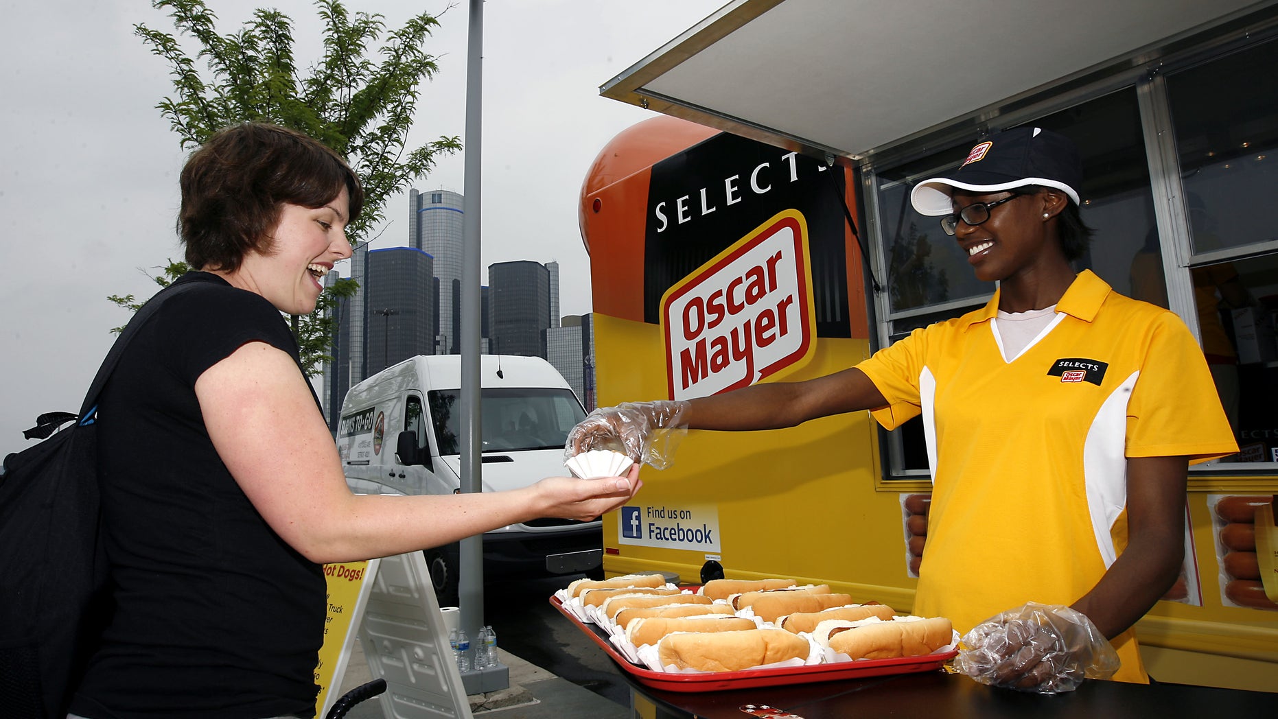 Julie Updyke of Ferndale, Mich., left, receives a complimentary hot dog from Teri Block of Southfield, Mich., as they gather around the first-ever, special edition Wienermobile Food Truck that serves Oscar Mayer Selects Beef Franks on Tuesday, June 21, 2011, in Detroit.