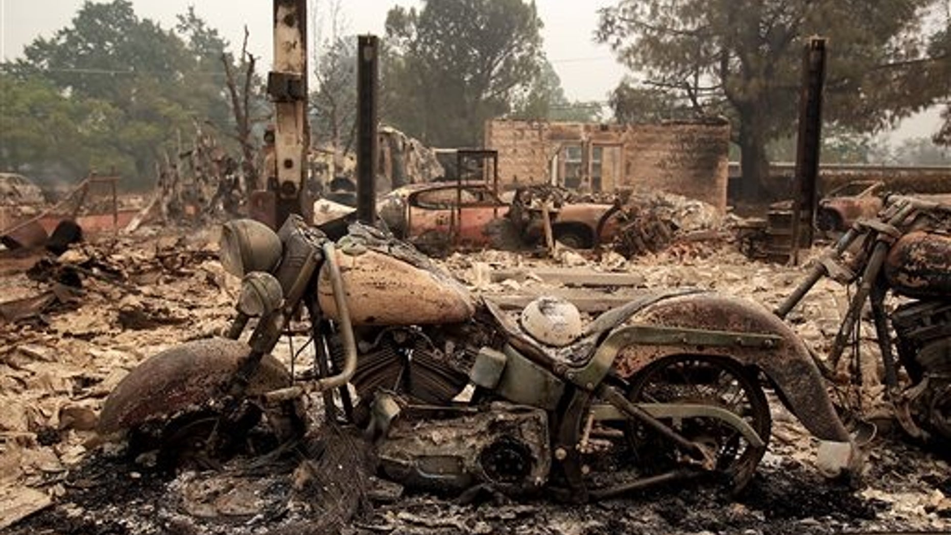 A motorcycle sits among burnt remains from a wildfire in Middletown, Calif., Sunday Sept. 13, 2015. Two of California's fastest-burning wildfires in decades overtook several Northern California towns, destroying homes and sending residents fleeing. (Kent Porter/The Press Democrat via AP) MANDATORY CREDIT