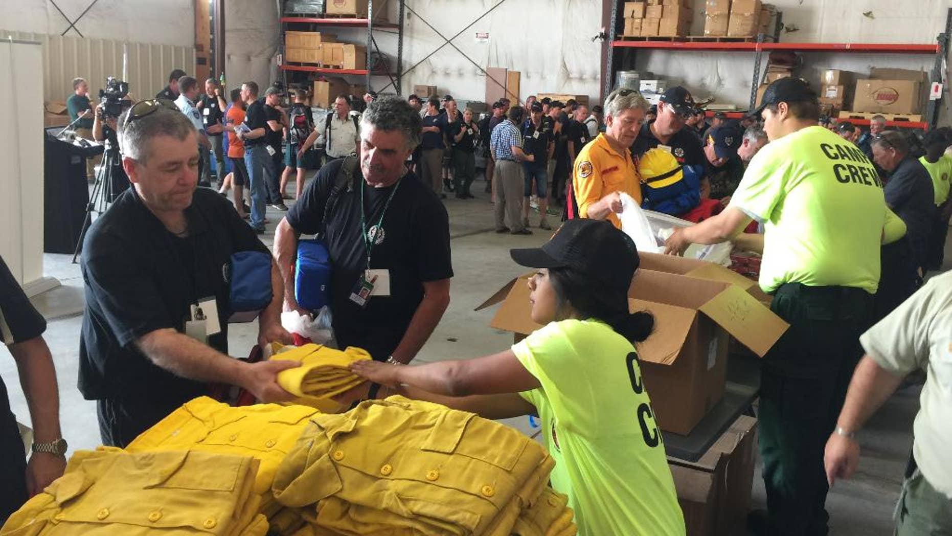 Warren Heslip, 47, of Southland, New Zealand, receives a yellow firefighting shirt on Monday, Aug. 24, 2015 at the National Interagency Fire Center in Boise, Idaho. Australian and New Zealand firefighters have arrived in the United States and prepared to fan out to help fight wildfires burning in several western states. (AP Photo/Keith Ridler)