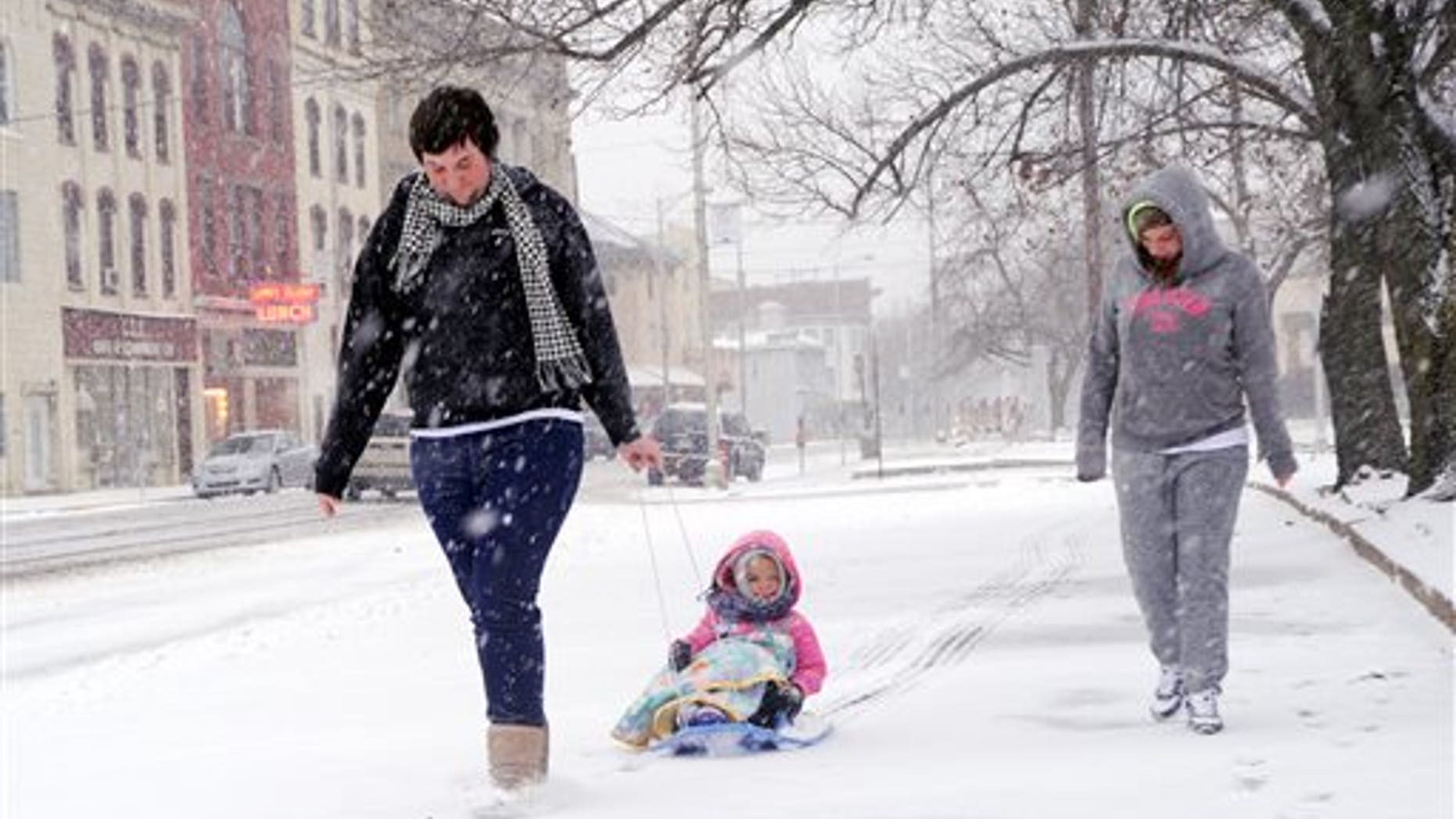 Marissa Birster, right, her little sister, Diamond Devalle, 3, and their friend Dylan Sessions walk along Indepedence Street in Shamokin on a snowy Saturday, Dec. 14, 2013. (AP Photo/The News-Item, Mike Staugaitis)