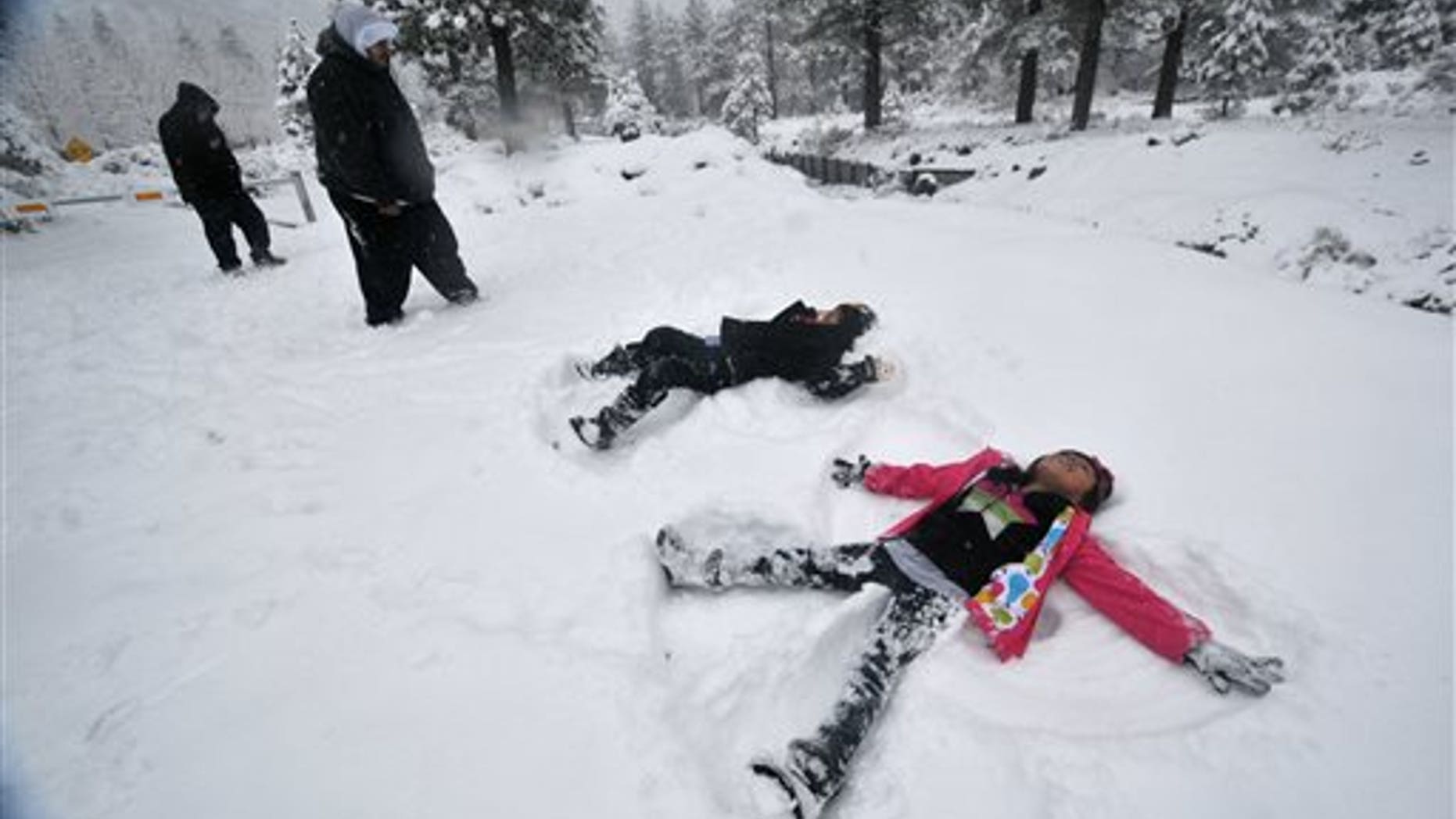 Darius Gomez, 9, center, and Amanda Lopez, 7, both from Palmdale, Calif, make snow angels together during their visit to Wrightwood, Calif, on Friday, Nov 22, 2013. (AP Photo/The Victor Valley Daily Press, David Pardo)