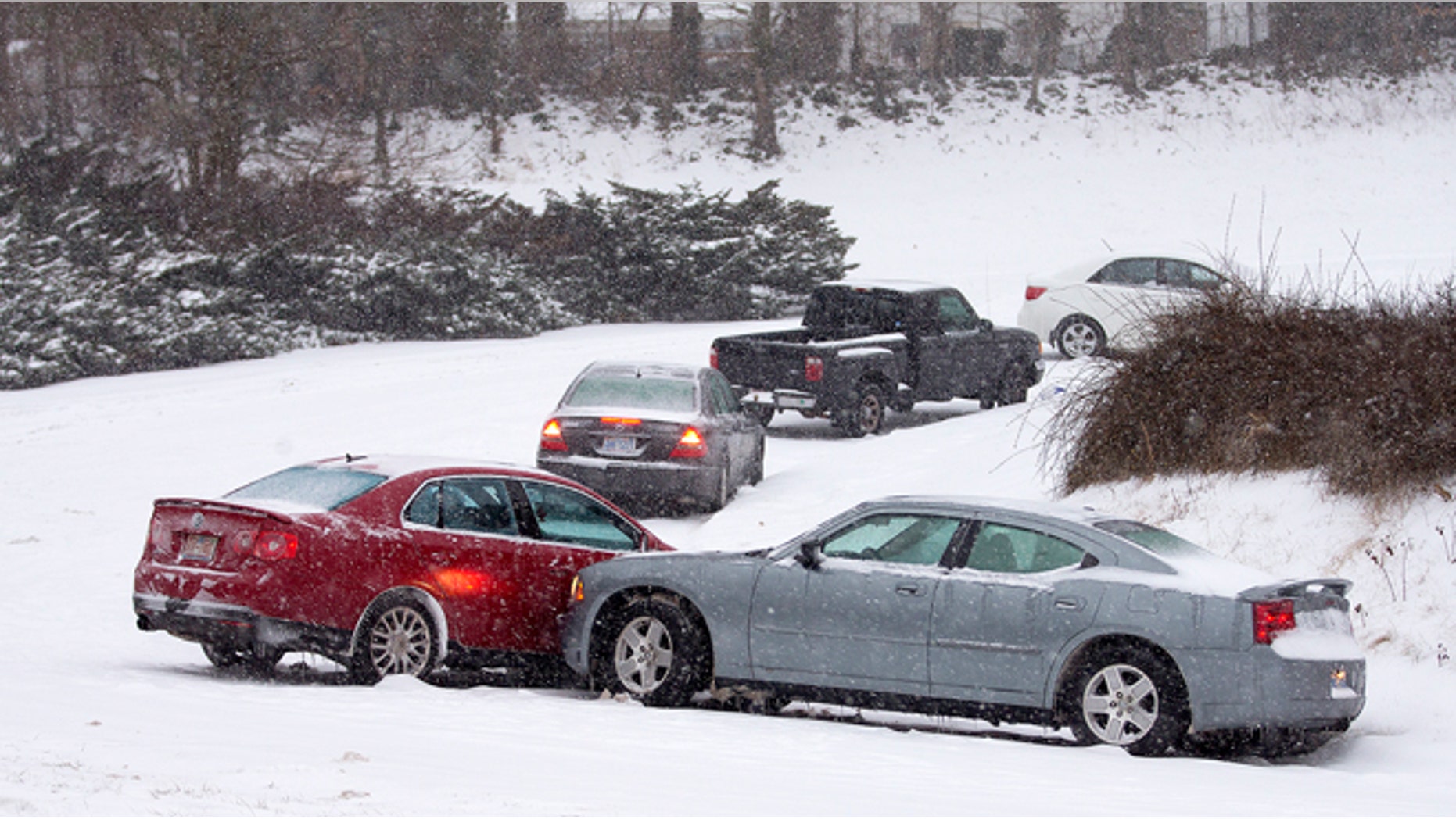 Cars that lost traction sit on the eastbound ramp from Joseph Bryan Boulevard to Holden Road during a snowfall in Greensboro, N.C., Wednesday, Feb. 12, 2014. A major winter slammed into North Carolina Wednesday, turning homebound commutes that typically take minutes into hours-long ordeals as traffic slowed to a slippery slog and threatening to leave many areas dark because of power outages. (AP Photo/News & Record, Nelson Kepley)