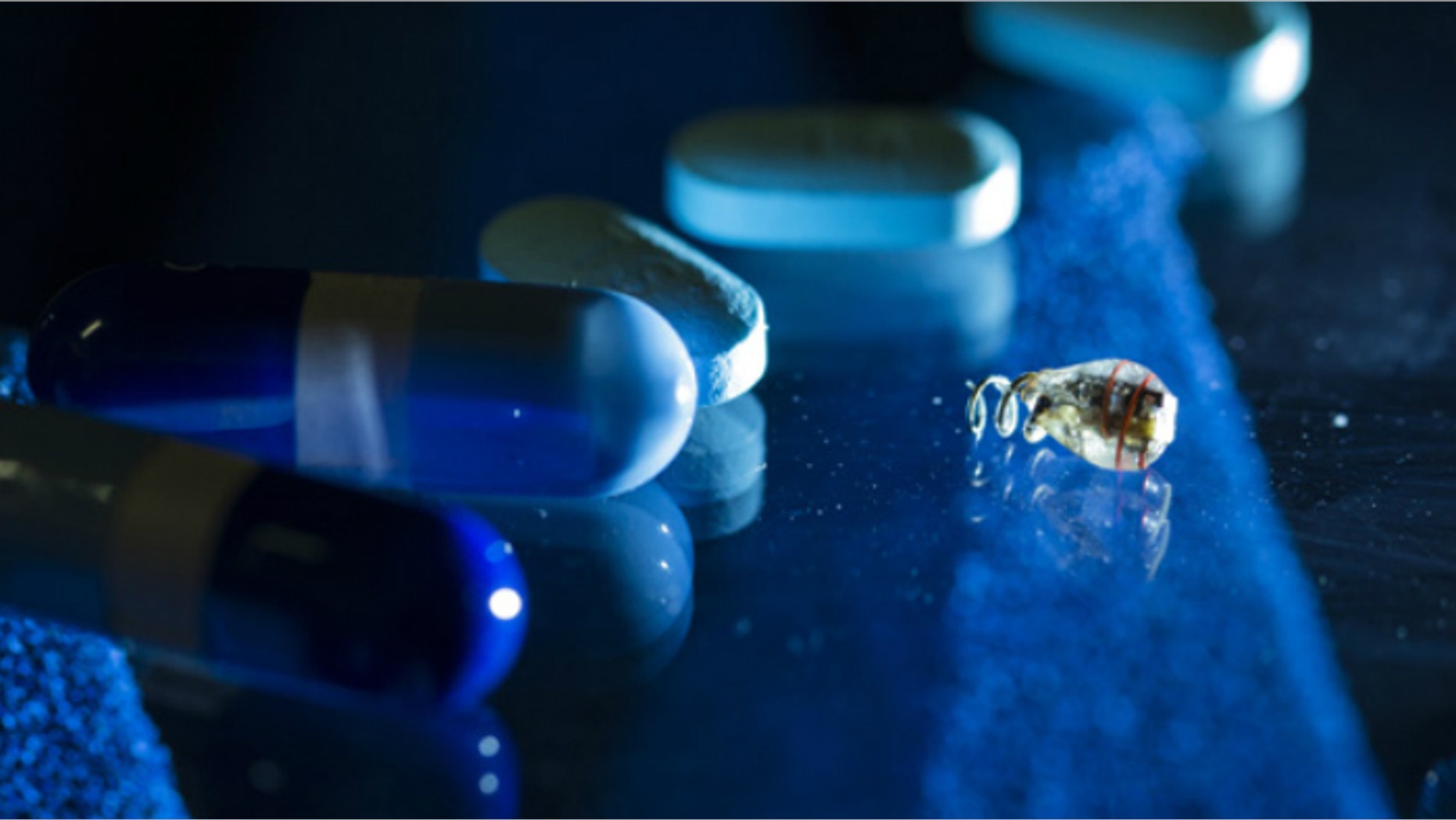 A battery-less electrostimulator next to medicinal pills for size comparison. The new powering method allows the device to be wirelessly powered deep inside the body.