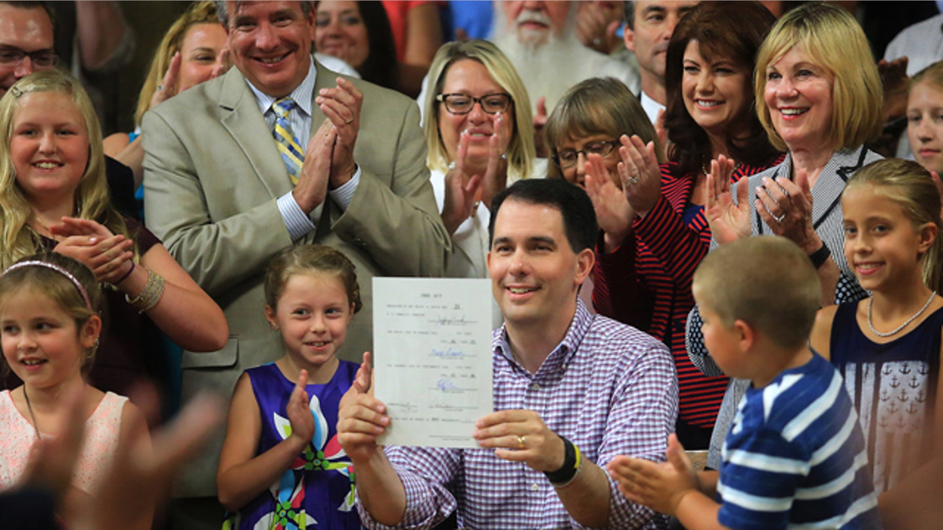 July 12, 2015: Wisconsin Governor Scott Walker displays a signed 2015-2017 state budget during a ceremony on the production floor of Valveworks USA in Waukesha, Wis. (John Hart/Wisconsin State Journal via AP)