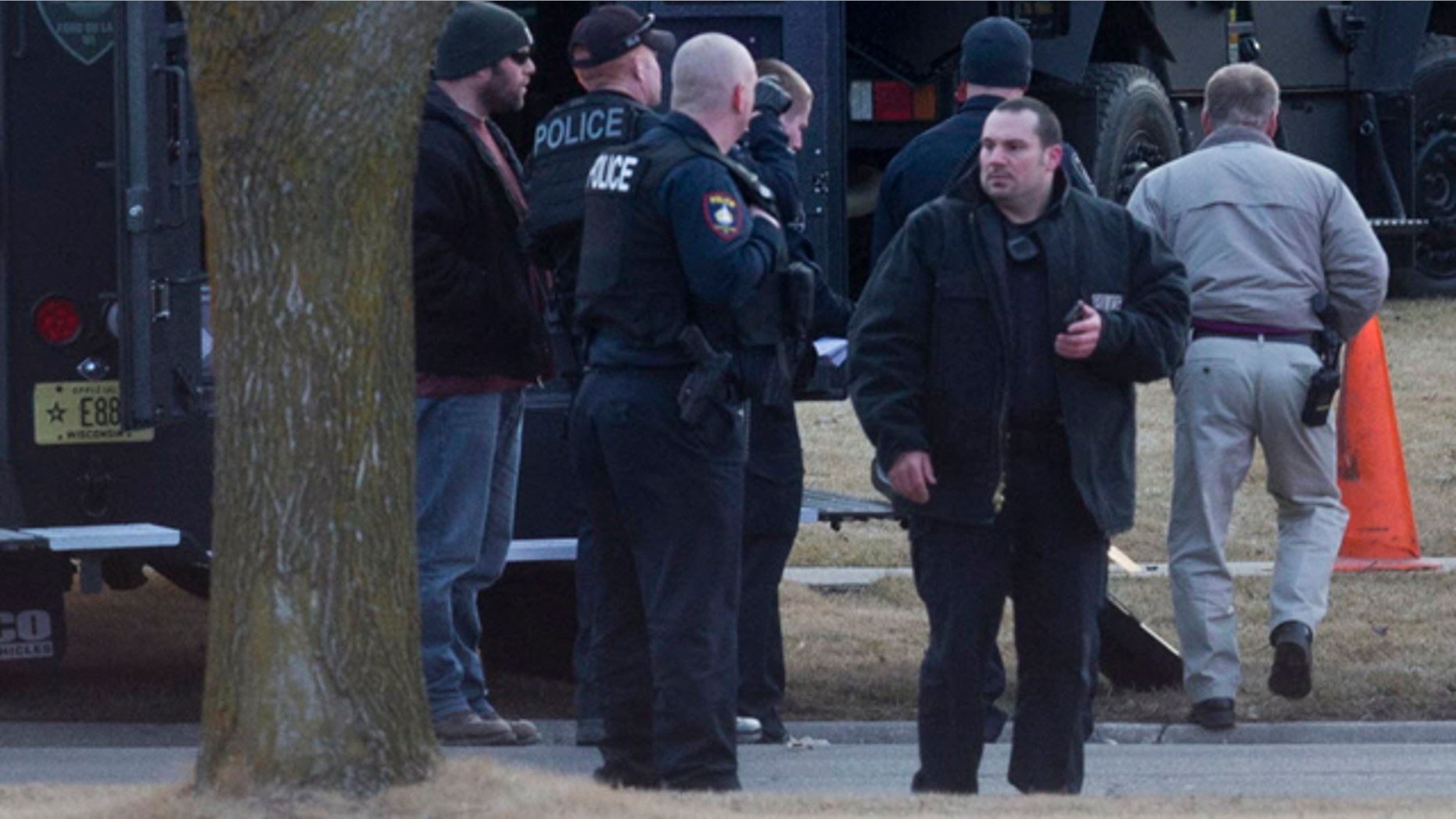 March 24, 2015: Law enforcement personnel gather at the scene of a shooting in Fond du Lac, Wis. Authorities say a Wisconsin state trooper was shot and killed in an exchange of gunfire with a person who matched the description of a bank robbery suspect. Police said the suspect also was killed. (AP Photo/Milwaukee Journal-Sentinel, Mark Hoffman)