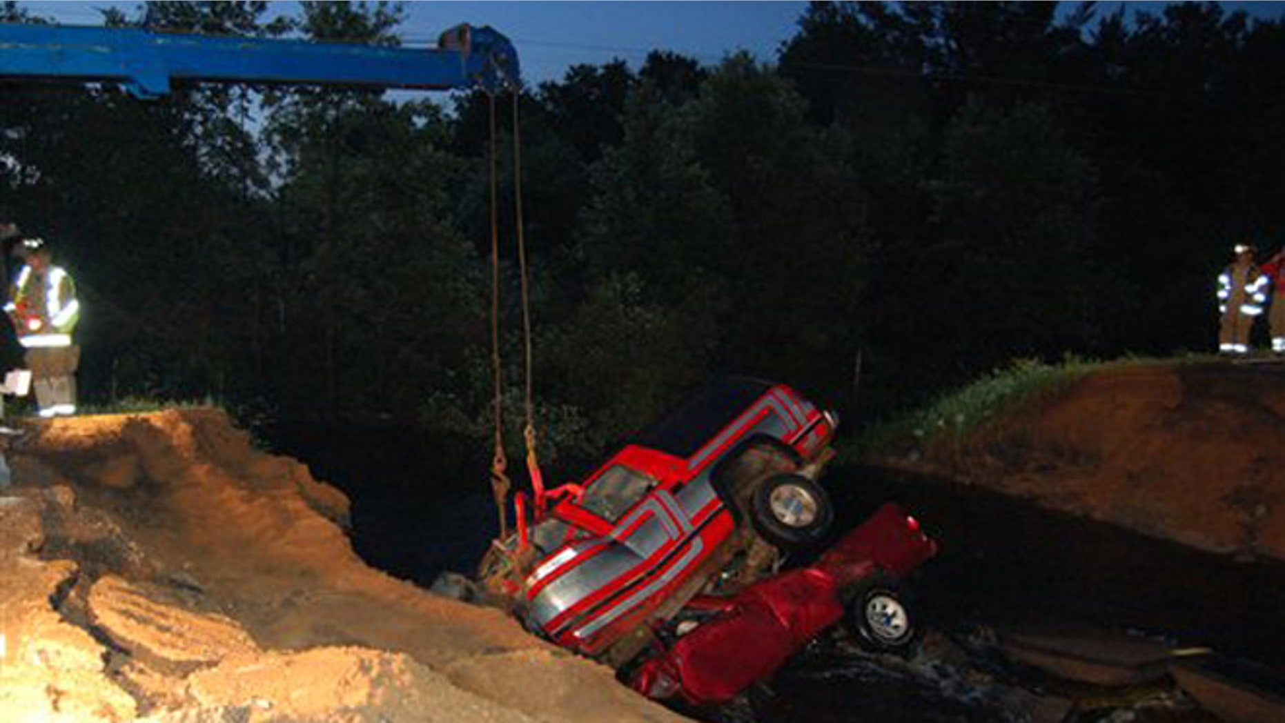 June 20, 2012: Clark County Sheriffs deputies watch as two vehicles are extracted from a washout hole after they crashed in to the large hole created by heavy rains, killing three people, on county road M near Neillsville, Wis.