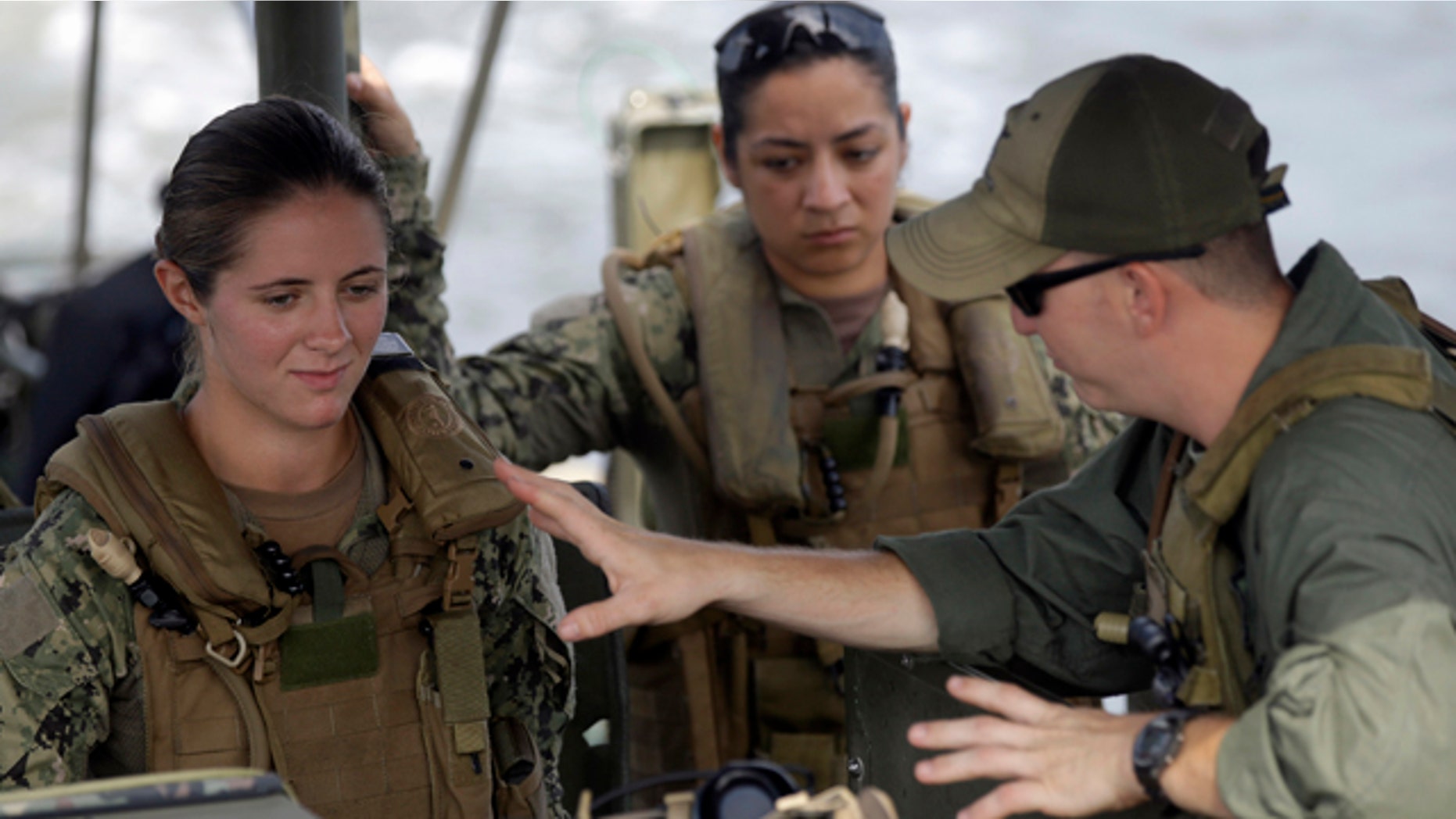 In this Aug. 13, 2013 file photo, U.S. Navy Master-at-Arms Third Class Danielle Hinchliff, left, and Master-at-Arms Third Class Anna Schnatzmeyer, center, participate in a U.S. Navy Riverine Crewman Course under instructor Boatswain's Mate Second Class Christopher Johnson, right, on a Riverine Assault Boat at Camp Lejeune, N.C. (AP Photo/Gerry Broome, File)
