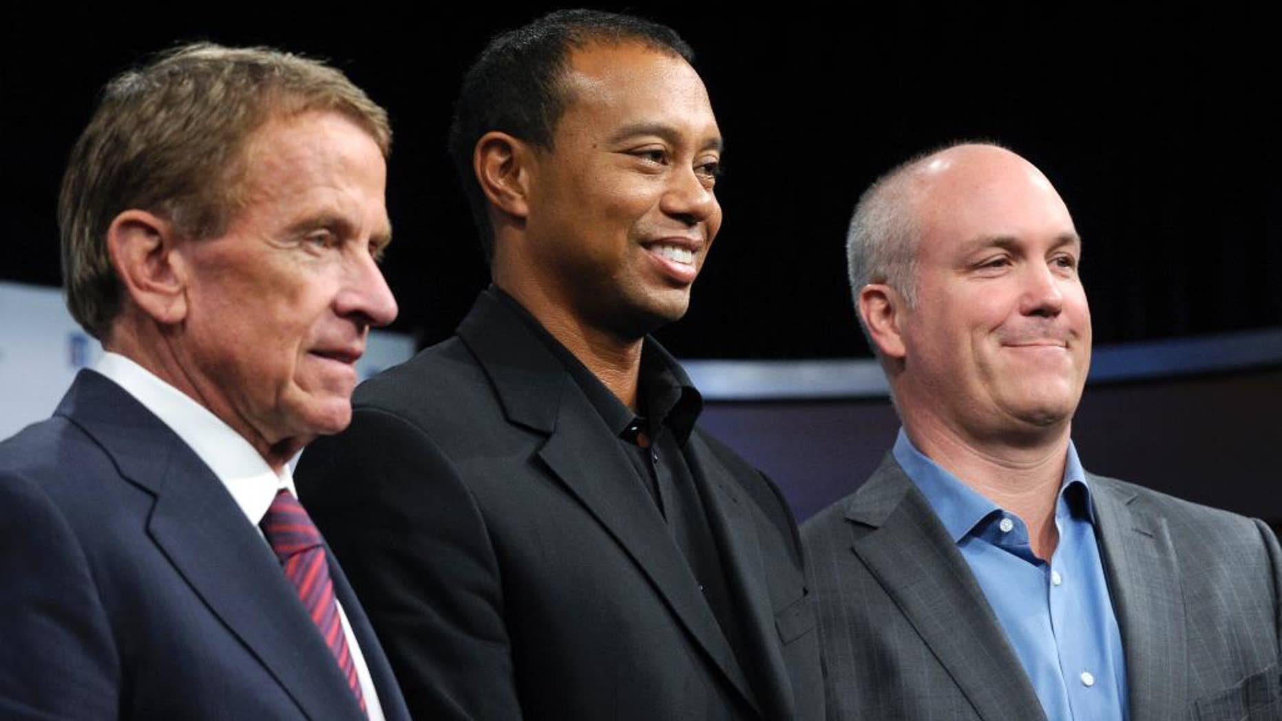 Tiger Woods, flanked by PGA Tour commissioner Tim Finchem, left and Quicken Loans Chief Executive Officer Bill Emerson, right, pose for a photo at the Newseum in Washington, Monday, March 24, 2014, after announcing that Quicken Loans had signed a multi-year agreement to become the title sponsor of the Quicken Loans National to be played at Congressional Country Club in Bethesda, Md., in June. (AP Photo/Susan Walsh)