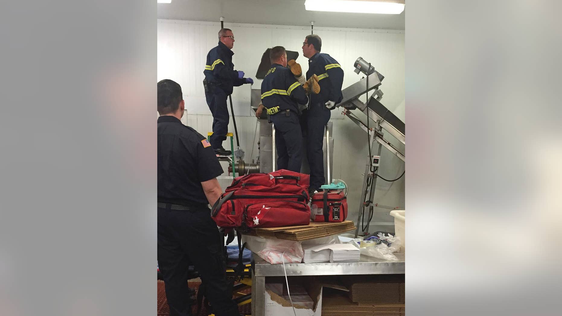 In this July 16, 2015 photo provided by the San Luis Obispo Fire Dept., a worker is assisted by fire personnel after his sleeve was caught in a meat grinder in San Luis Obispo, Calif. Fire officials say the employee at a wholesale California grocer is lucky to be alive after getting caught in a running meat grinder. The worker's sleeve got caught and was being pulled in when a co-worker heard his screams and shut the machine off. Fire crews had to pry the machine open to get the worker out who suffered a broken arm. (Garret Olson/San Luis Obispo Fire Dept. via AP)