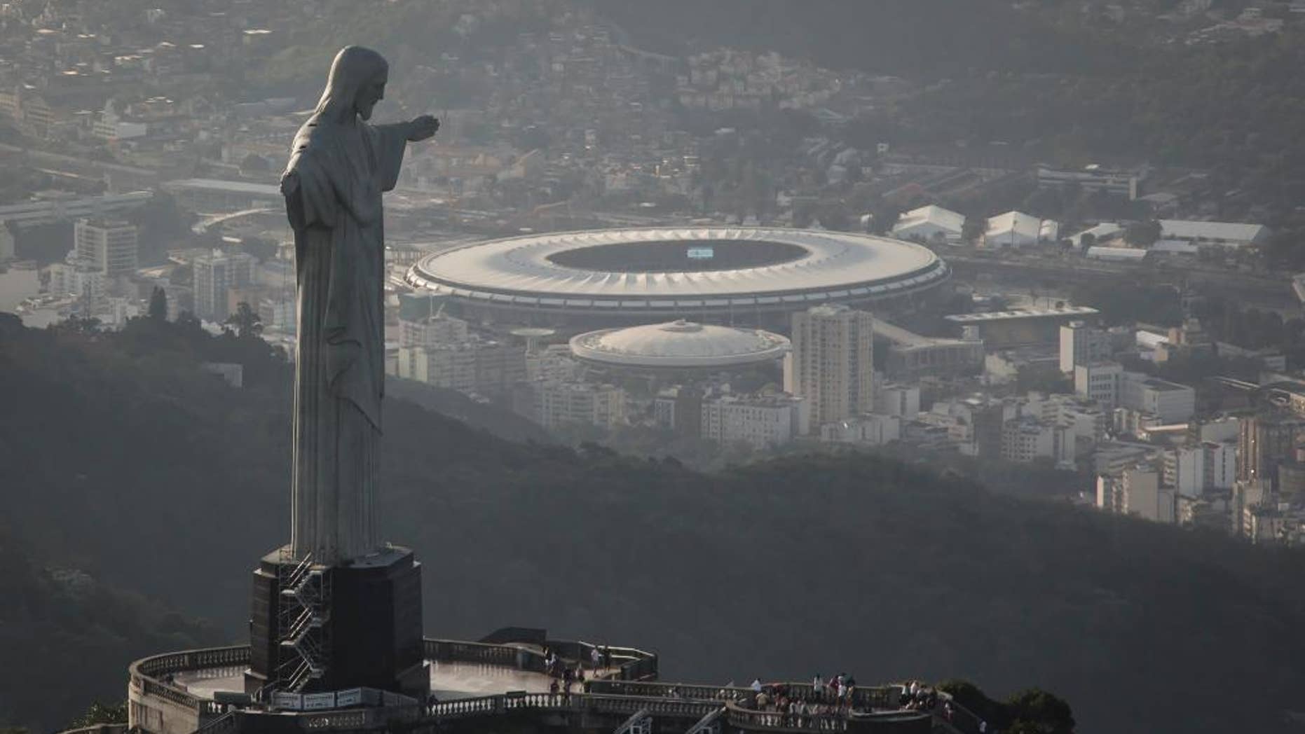 In this May 13, 2014, photo,This aerial view shot through an airplane window shows the Maracana stadium behind the Christ the Redeemer statue in Rio de Janeiro, Brazil. As opening day for the World Cup approaches, people continue to stage protests, some about the billions of dollars spent on the World Cup at a time of social hardship, but soccer is still a unifying force. The international soccer tournament will be the first in the South American nation since 1950. (AP Photo/Felipe Dana, File)