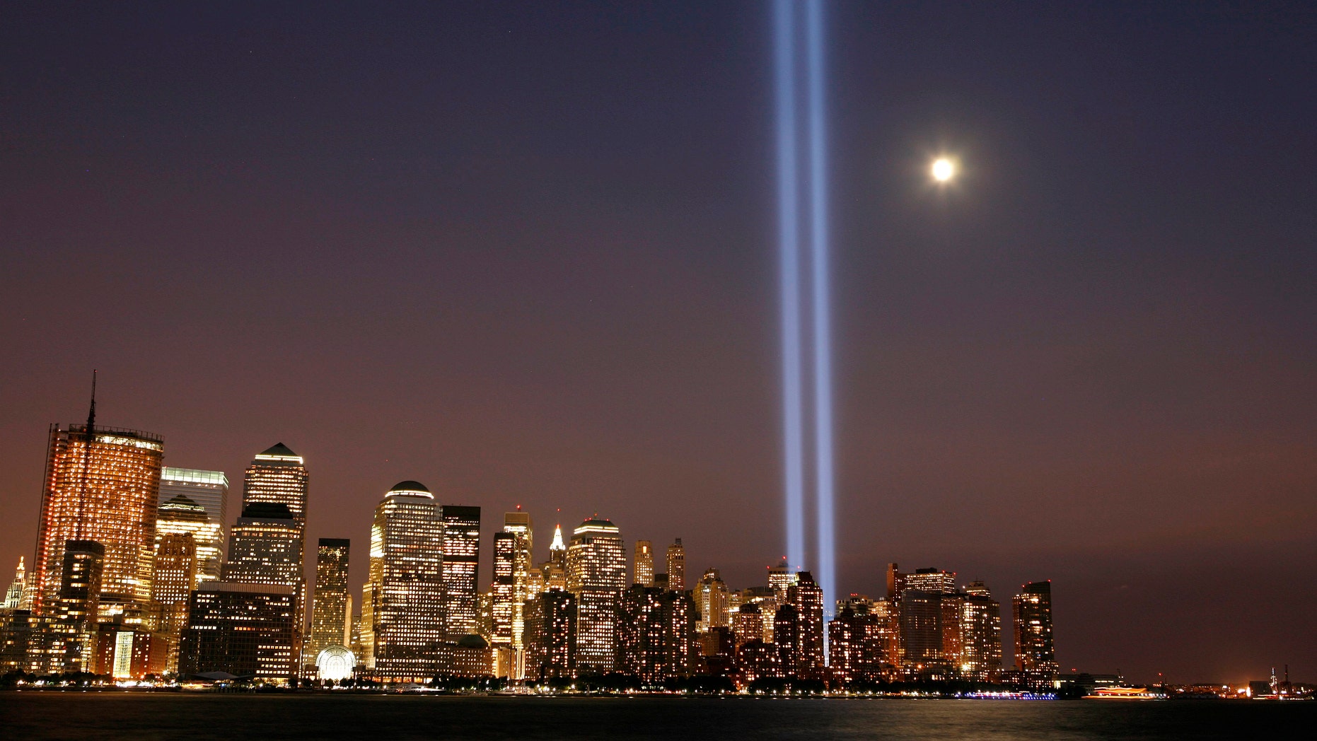 The moon rises over lower Manhattan as the "Tribute in Lights" illuminates the sky.