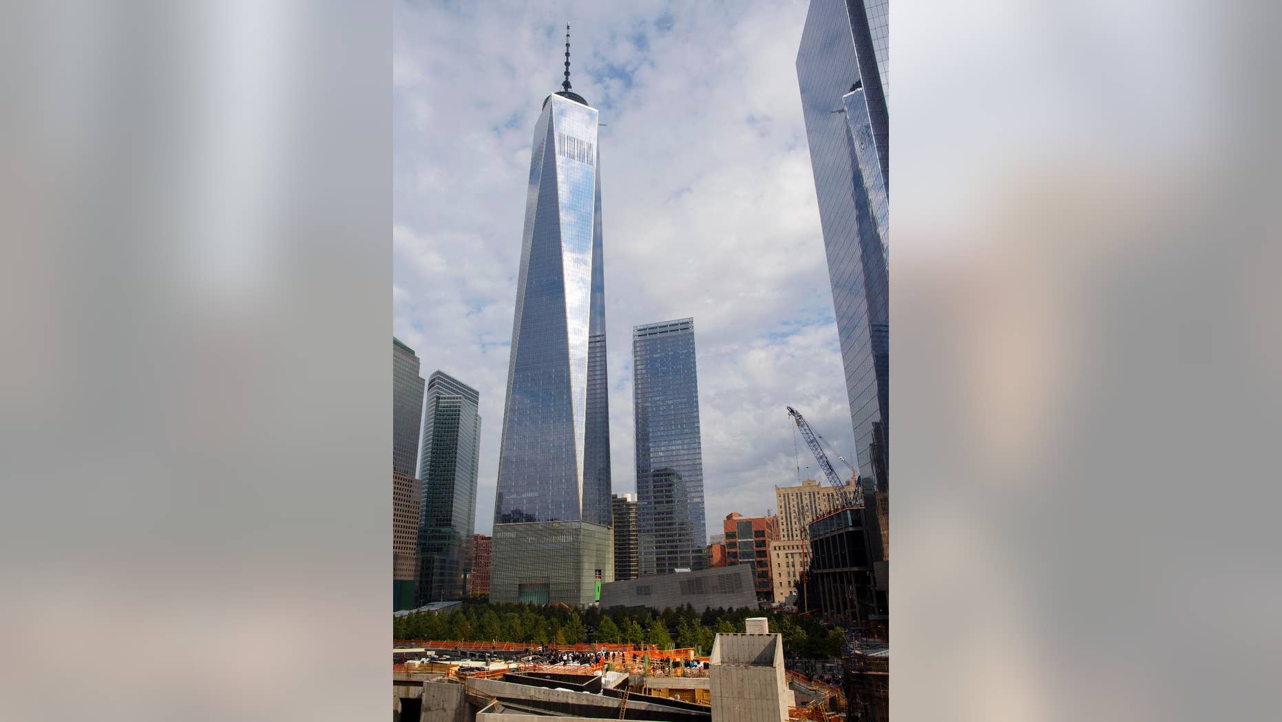 File-This Oct. 18, 2014, file photo shows One World Trade Center in the background, as people gather, bottom, for a groundbreaking ceremony at the site of the St. Nicholas National Shrine, in New York. Thirteen years after the 9/11 terrorist attack, the resurrected World Trade Center is again opening for business, marking an emotional milestone for both New Yorkers and the nation. Publishing giant Conde Nast will start moving Monday, Nov. 3, 2014, into One World Trade, a 104-story, $3.9 billion skyscraper that dominates the Manhattan skyline. It is America's tallest building. (AP Photo/Craig Ruttle, File)