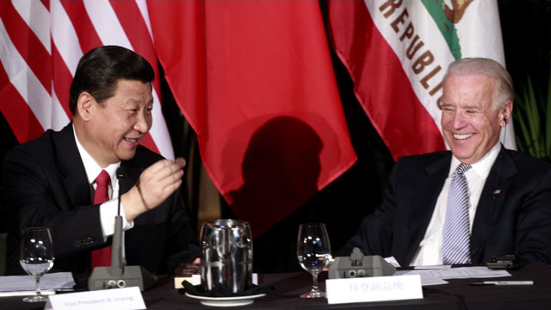 Feb. 17, 2012: Chinese Vice President Xi Jinping, left with Vice President Joe Biden, shows off a chocolate-covered macadamia nut, given to him by Hawaii Governor Neil Abercrombie, at the start of a meeting of Chinese and American governors, at Disney Hallin Los Angeles.