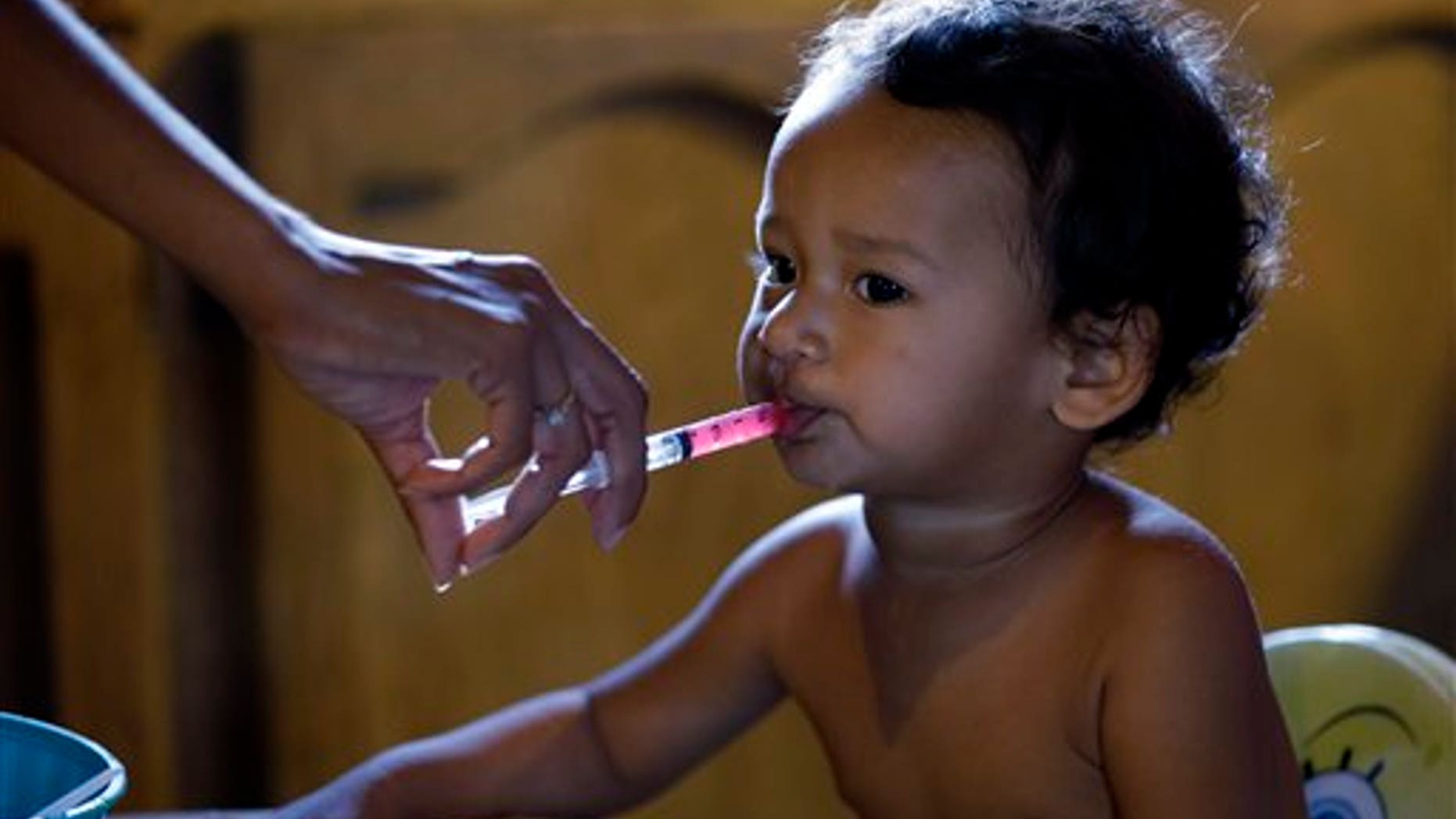 Yahiden Lopez takes medication from his mother at their home, in Alamo, Texas.