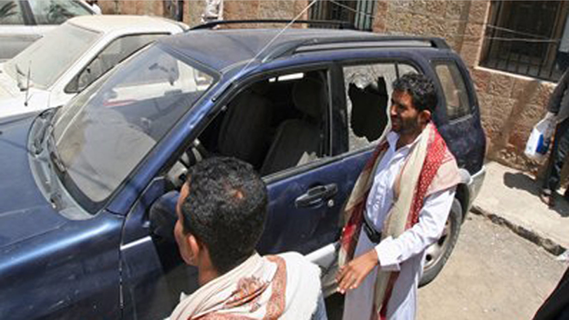 Mar. 18, 2012: Yemenis gather around a damaged vehicle purported to belong to an American teacher shot by gunmen in Taiz, Yemen.