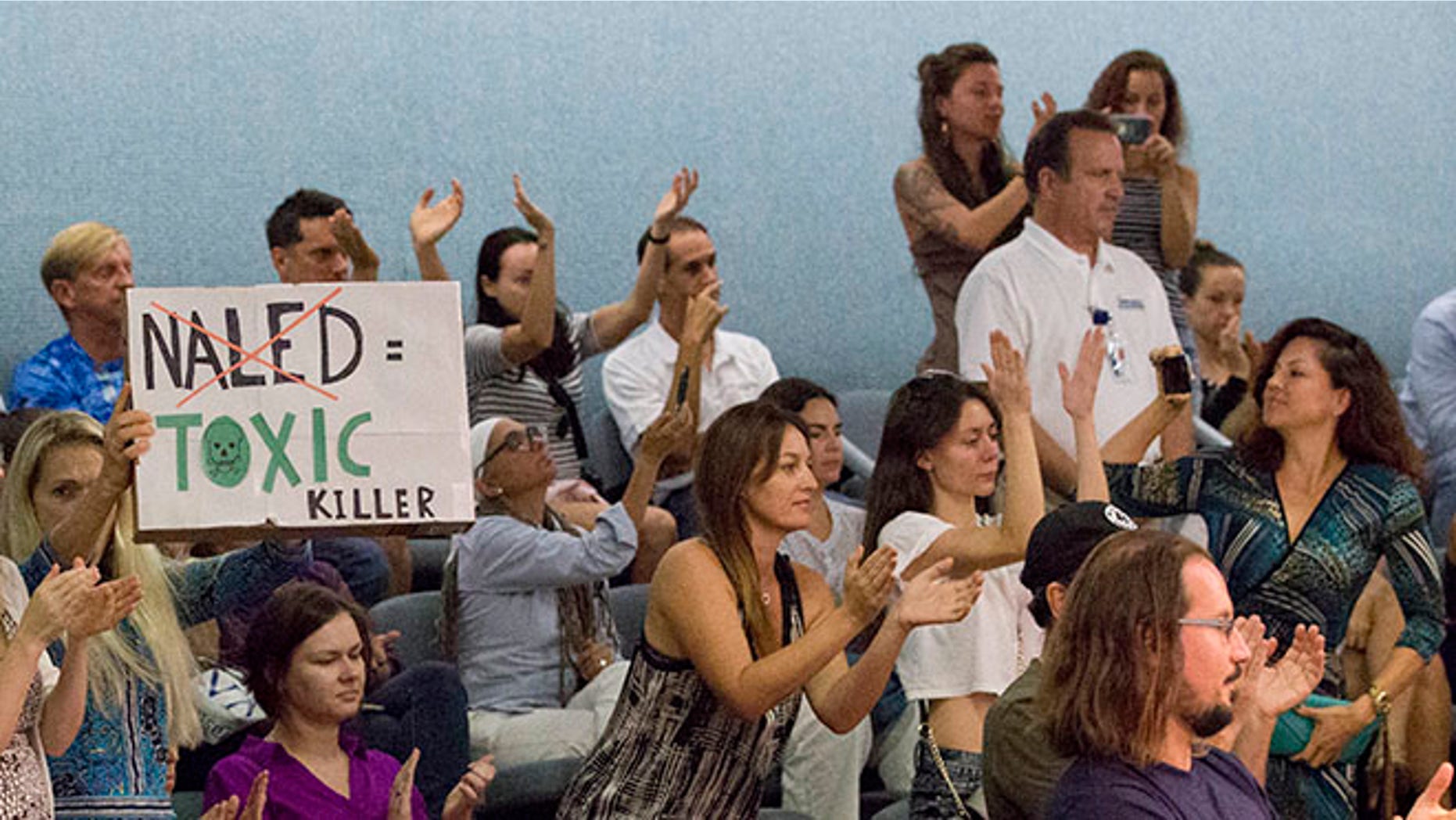 Demonstrators cheer as they pack a Miami Beach, Fla., city commission meeting, Wednesday, Sept. 14, 2016, in Miami Beach. Opponents want to stop the aerial spraying of the insecticide naled, used to combat the Aedes aegypti mosquito. They say the pesticide can cause health problems in people. (AP Photo/Wilfredo Lee)