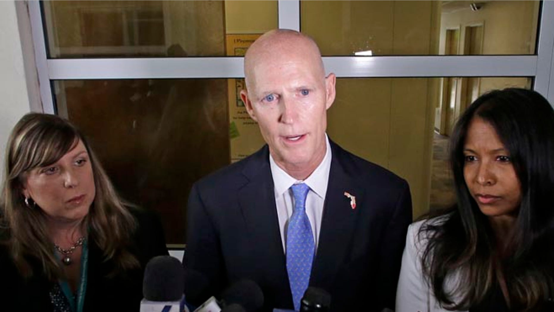Gov. Rick Scott flanked by Dr. Paula Thaqi, Director of the Broward County Health Department, left, and Dr. Celeste Philip, State Surgeon General.