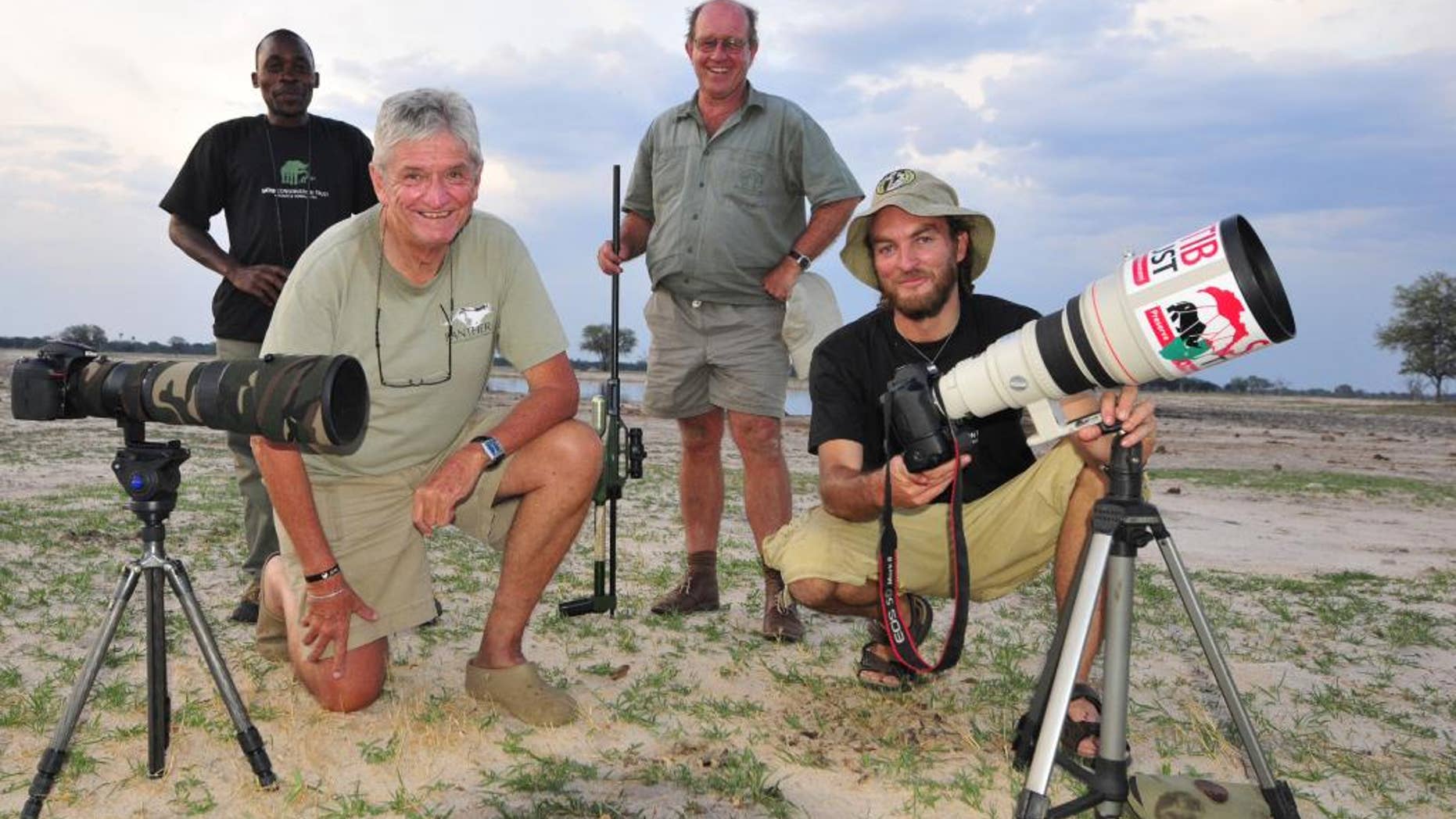 In this photo taken Nov. 9, 2014 photographer Brent Stapelkamp, front right, with colleagues in the Hwange National Park, Zimbabwe. Stapelkamp, a lion researcher and part of a team that had tracked and studied Cecil the lion for nine years darted him and attached a collar last year. He was probably the last person to get up close before Minnesota dentist Walter Palmer killed the now-famous lion with the bushy black mane and, aided by a Zimbabwean professional hunter, cut off its head and skin for trophies. (AP Photo/Derek Whalley)