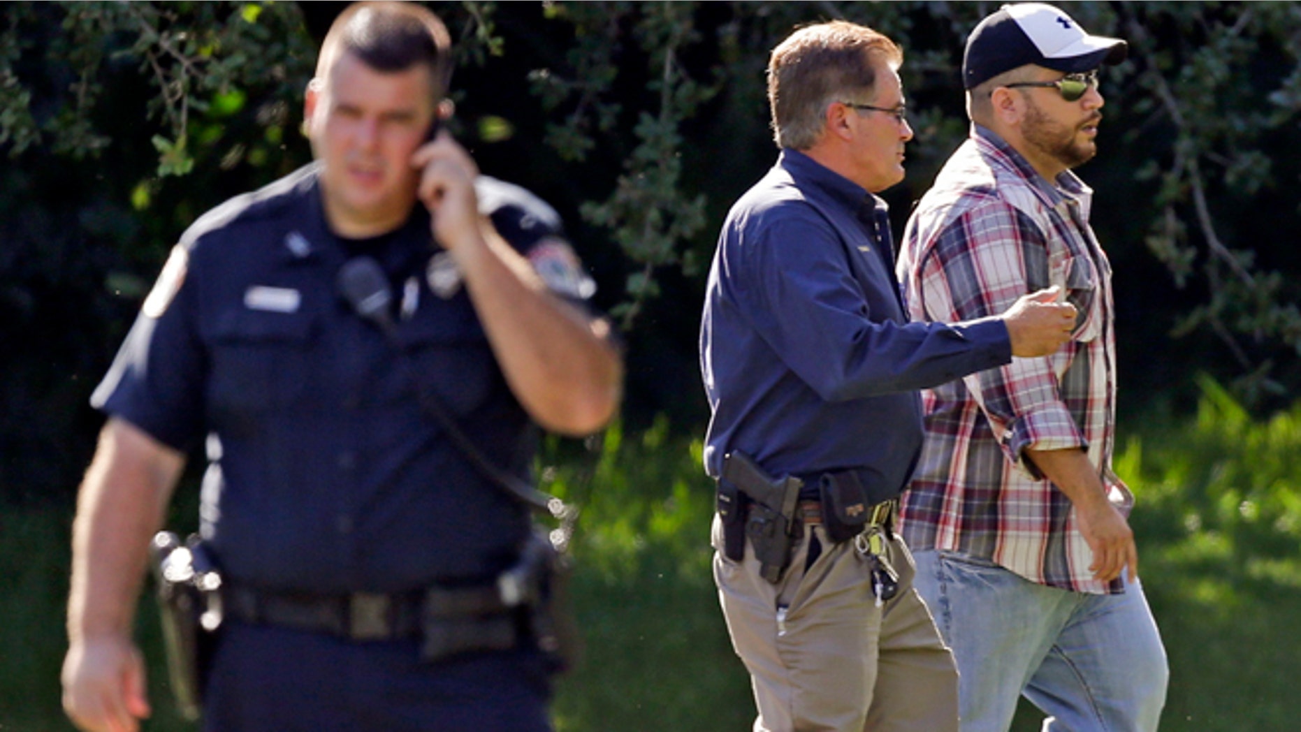 George Zimmerman, right, is escorted to a home by a Lake Mary police officer, center, Monday, Sept. 9, 2013, in Lake Mary, Fla., after a domestic incident in the neighborhood where Zimmerman and his wife Shellie had lived during his murder trial. Zimmerman's wife says on a 911 call that her estranged husband punched her father in the nose, grabbed an iPad out of her hand and smashed it and threatened them both with a gun. Zimmerman was recently found not guilty for the 2012 shooting death of Trayvon Martin. (AP Photo/John Raoux)