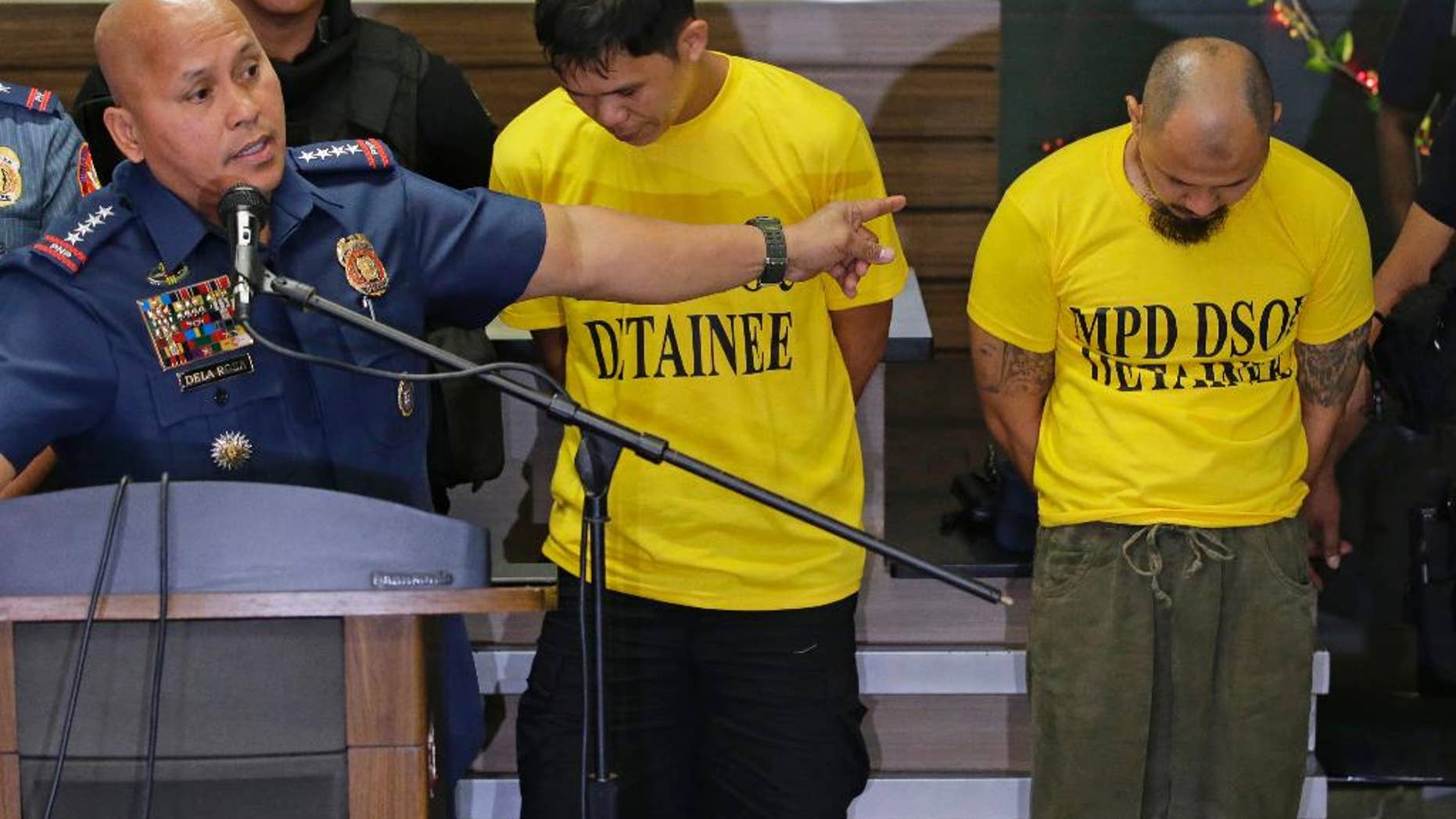 Suspects Jiaher Guinar, center, and Rashid Kilala, right, presented to reporters at police headquarters in Quezon city, north of Manila, Philippines.