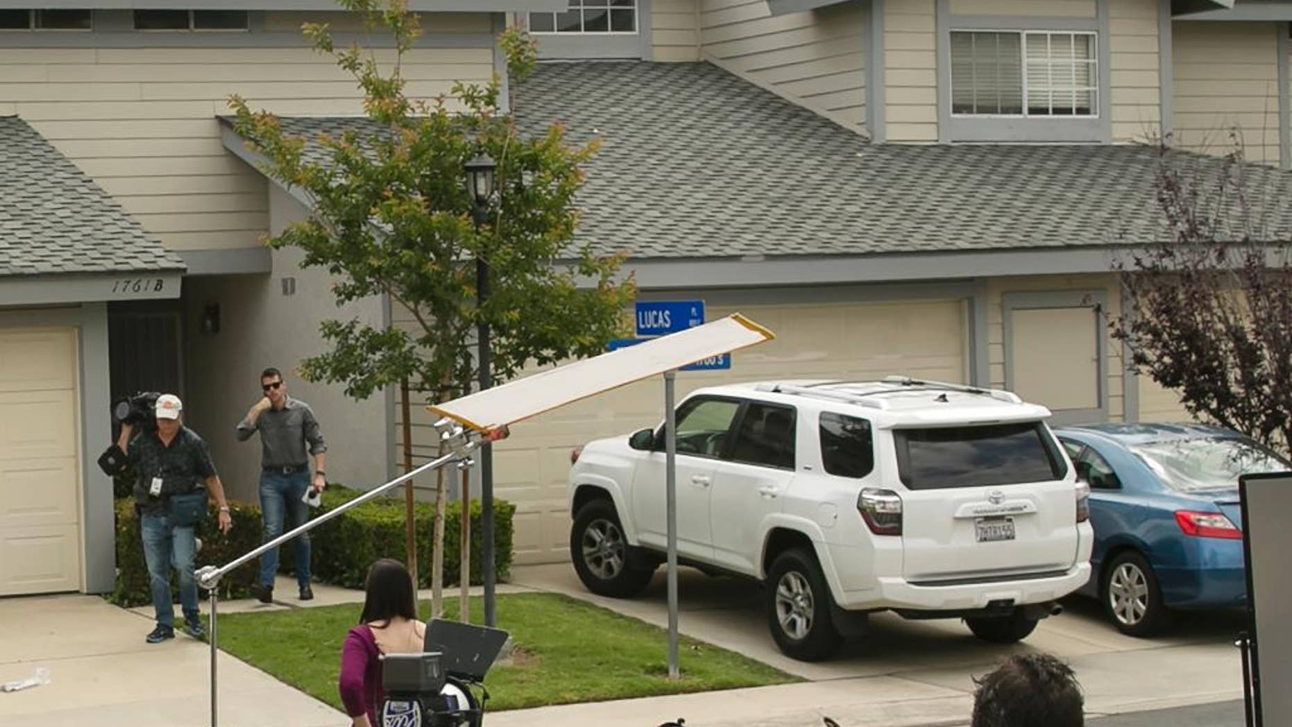 Members of the media stand outside the home of Syed Raheel Farook, the elder brother of San Bernardino gunman Syed Rizwan Farook, after the FBI served a warrant to the location, in Corona, Calif., Thursday, April 28, 2016. Syed Raheel Farook was arrested with two others Thursday in what prosecutors say was a marriage scheme to fraudulently allow one of them to remain in the United States. (AP Photo/Damian Dovarganes)