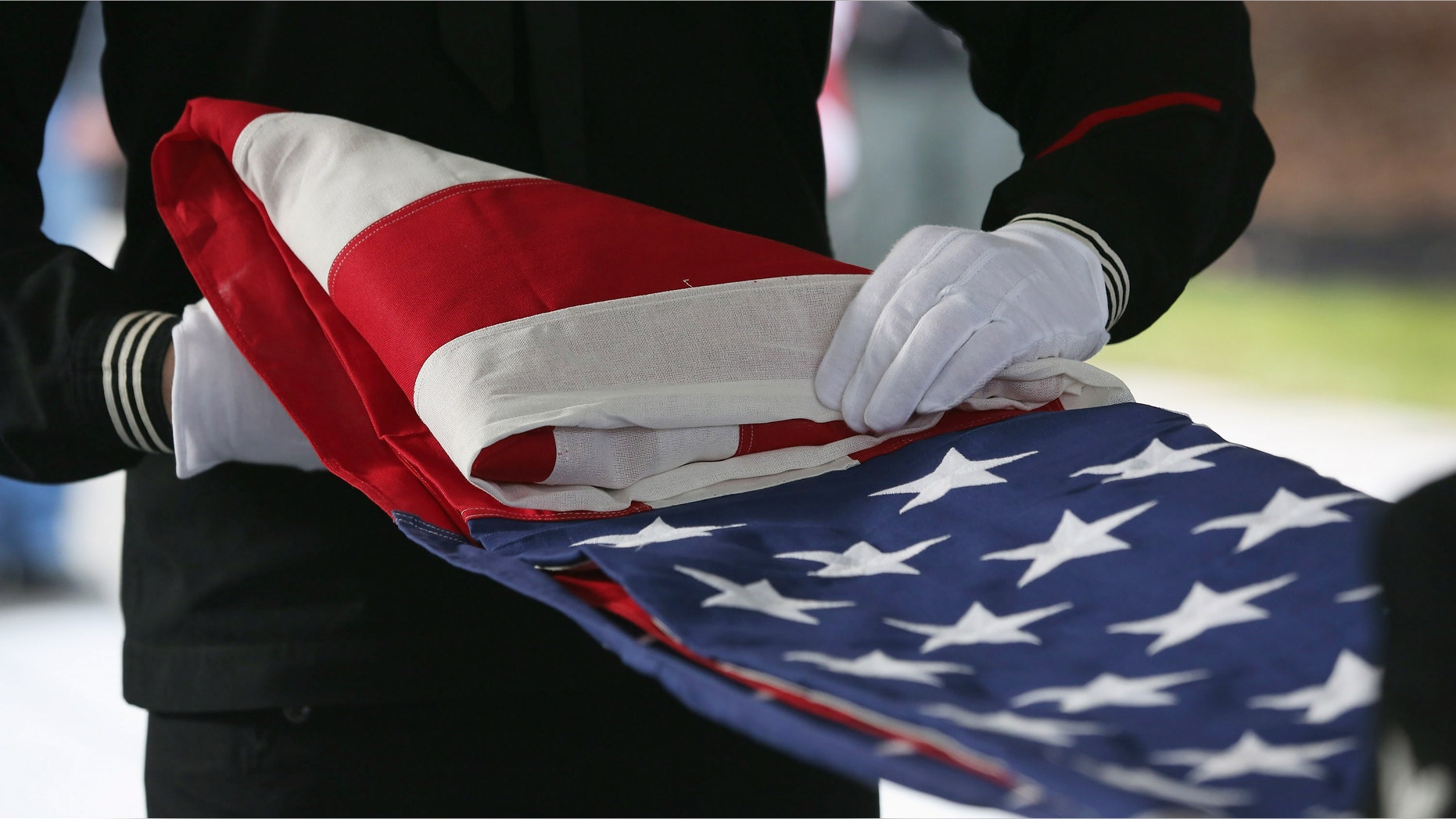 WADING RIVER, NY - DECEMBER 11: A U.S. Navy honor guard folds an American flag after removing it from the casket of Hurricane Sandy victim David Maxwell, before his burial at the Calverton National Cemetery on December 11, 2012 near the Wading River hamlet of Long Island, New York. Maxwell, 66, was the last of Sandy's victims found on the Staten Island borough of New York City, when his body was discovered in his Midland Beach home 11 days after the storm. A Vietnam veteran, he was buried at the national cemetery, accompanied by honor guards from the Catholic War Veterans and the Patriot Guard Riders. (Photo by John Moore/Getty Images)