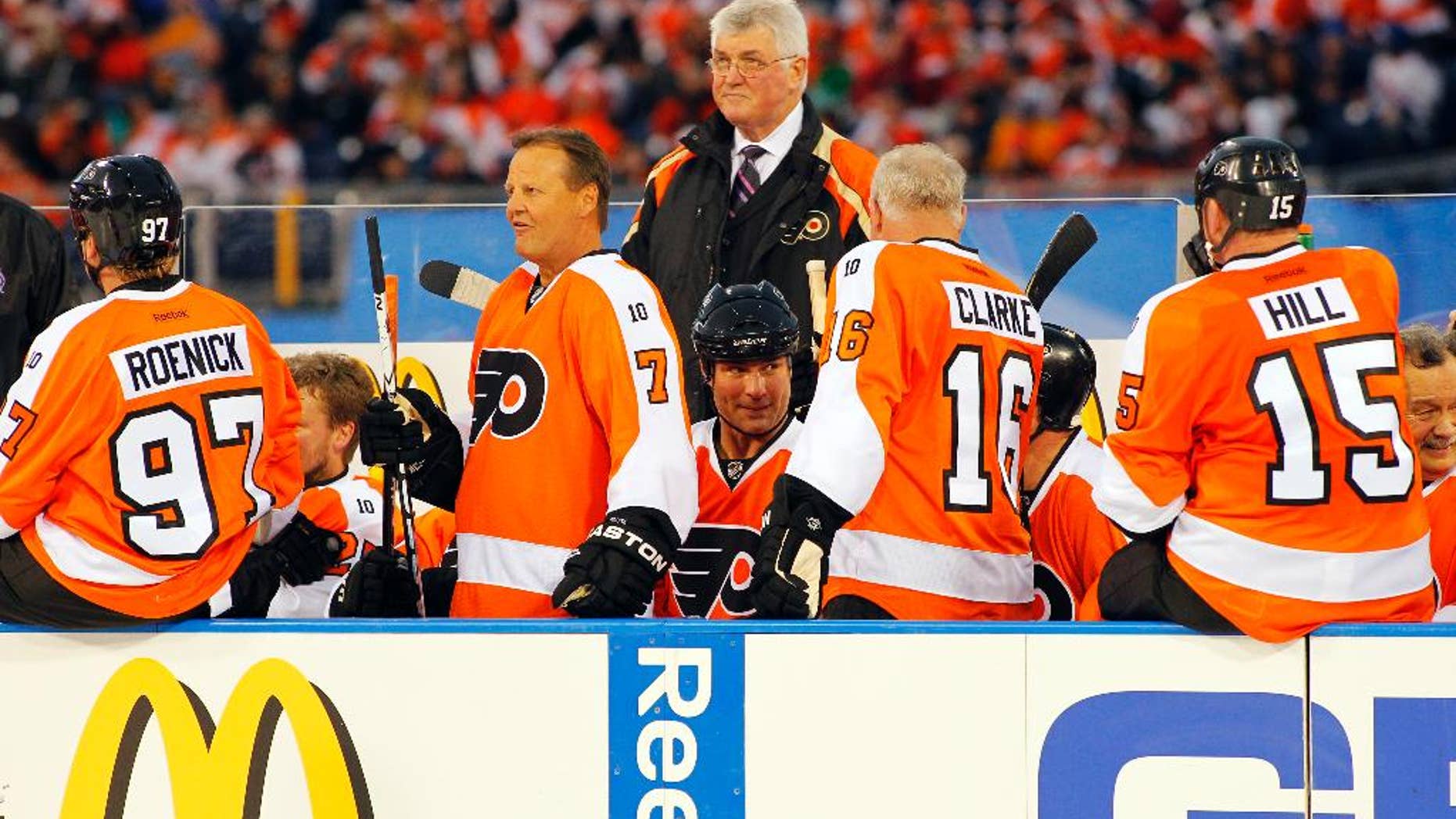 FILE - In this Dec. 31, 2011, file photo, members of the Philadelphia Flyers Alumni team gather on the bench in front of coach Pat Quinn, center, during the Winter Classic Alumni hockey game with the New York Rangers Alumni team in Philadelphia. Quinn, a former defenseman and longtime NHL coach and executive who brought a gruff and passionate presence to hockey across the decades, has died at 71. He died Sunday, Nov. 23, 2014, in Vancouver, British Columbia, after a long illness, the Hockey Hall of Fame and the Western Hockey League's Vancouver Giants said Monday. (AP Photo/Tom Mihalek, File)