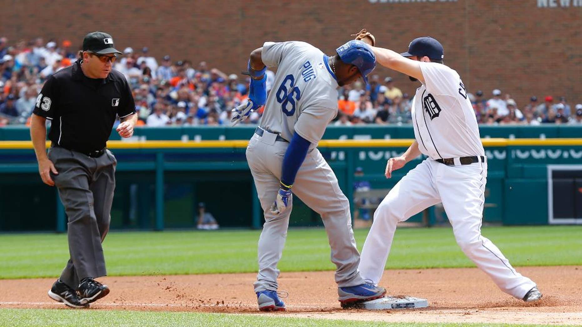 Detroit Tigers third baseman Nick Castellanos shows the ball to third base umpire Paul Schrieber after tagging third base before Los Angeles Dodgers' Yasiel Puig (66) could tag up on a Hanley Ramirez fielders choice in the first inning of a baseball game in Detroit, Wednesday, July 9, 2014. Puig was out on the play. (AP Photo/Paul Sancya)