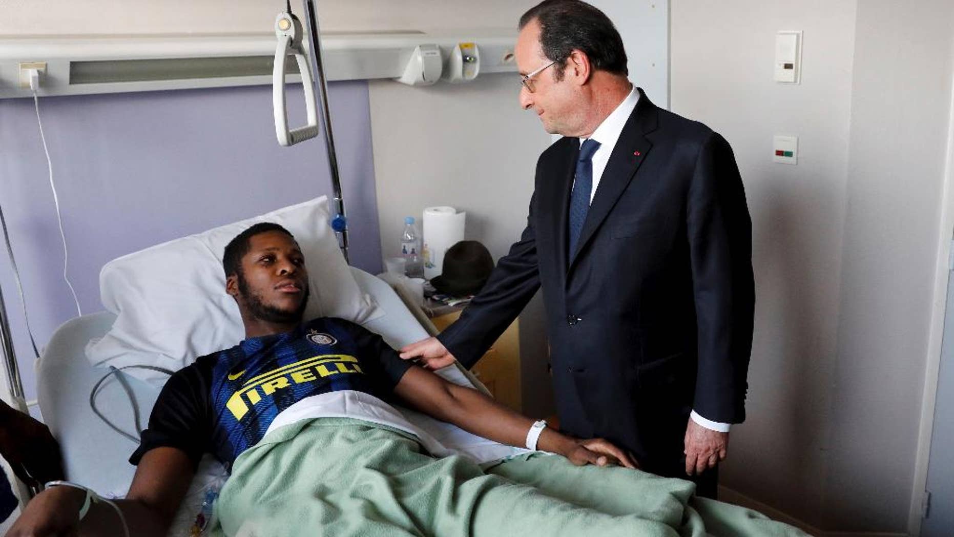 In this photo dated Tuesday, Feb. 7, 2017, provided by Le Parisien, France's President Francois Hollande, right, stands next to alleged victim, identified only by his first name, Theo, at Robert Ballanger hospital in Aulnay-sous-Bois, north of Paris, France. Violence in suburbs northeast of Paris have now spread to at least five towns, erupting after a young black man was allegedly sodomized with a police officer's baton last week, during an identity check. One officer was charged Sunday with aggravated rape and three others were charged with aggravated assault. (Arnaud Journois/Le Parisien via AP)