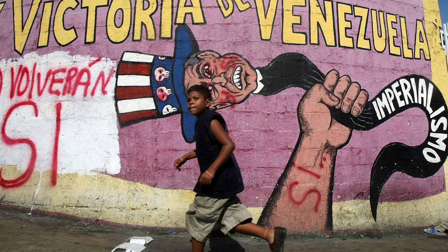 CARACAS, VENEZUELA - DECEMBER 01: A boy runs past anti-American propaganda and graffiti reading "Si" signifying support for a referendum on changes to the Constitution introduced by Venezuelan President Hugo Chavez December 1, 2007 in Caracas, Venezuela. Sunday's referendum proposes an elimination of term limits for Chavez and a transformation of Venezuela into a "socialist economy." (Photo by Mario Tama/Getty Images)