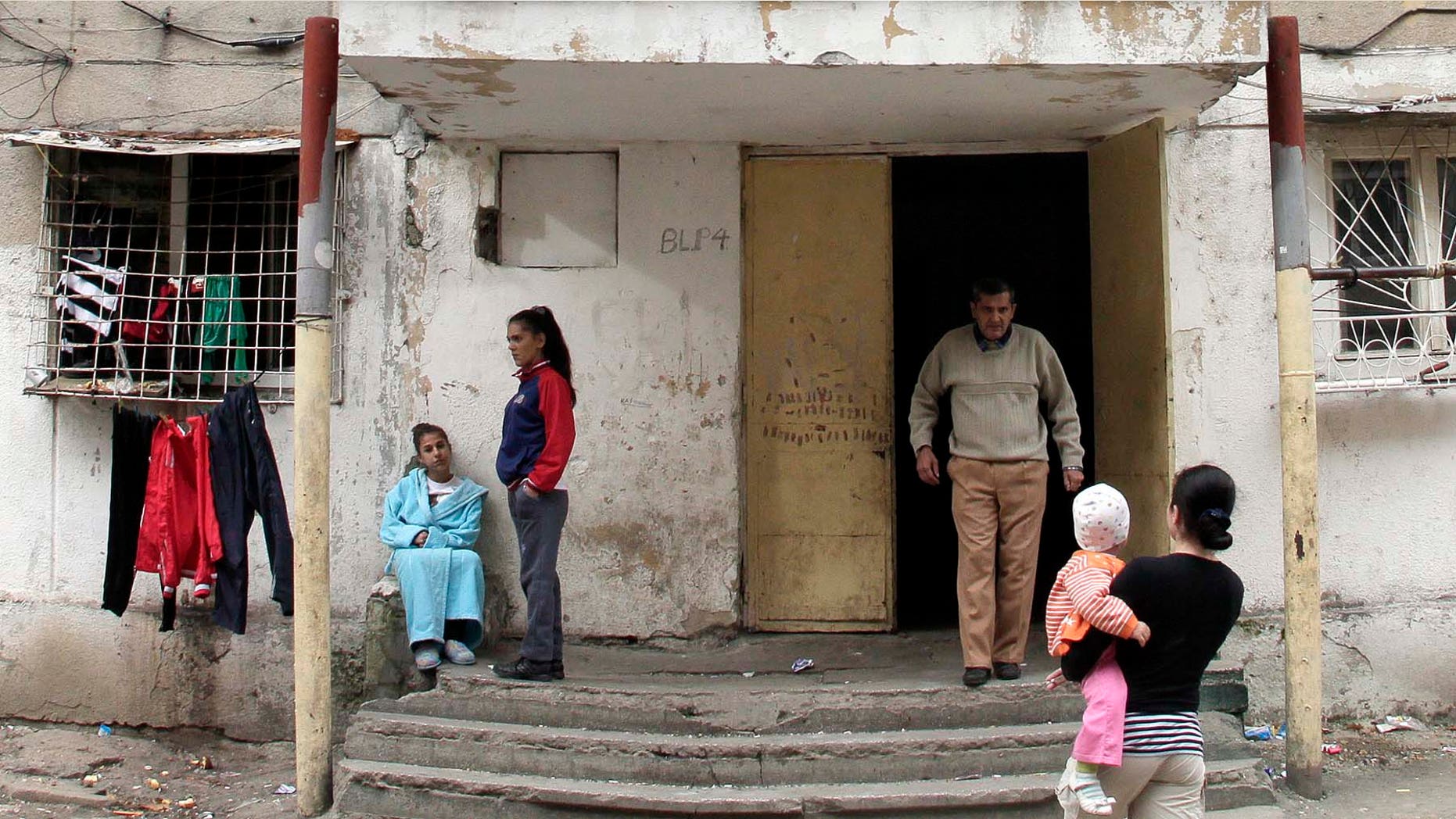 Romanian Gypsy residents are seen outside the apartment block that was home to Romanian girl that gave birth in Spain last week in Bucharest, Romania, Tuesday, Nov. 9, 2010. The former neighbors of a Romanian girl who gave birth last week in Spain on Tuesday claimed that she is more than 10 years old. Neighbors gathered outside the shabby four-story apartment building where the girl spent her early years before moving to Spain. They told the Associated Press they were indignant about "lies" that the girl was just 10 when she became a mother. Several neighbors in Bucharest's impoverished Ferentari district said they believed she was between 13 and 15 years old.(AP Photo/Vadim Ghirda)