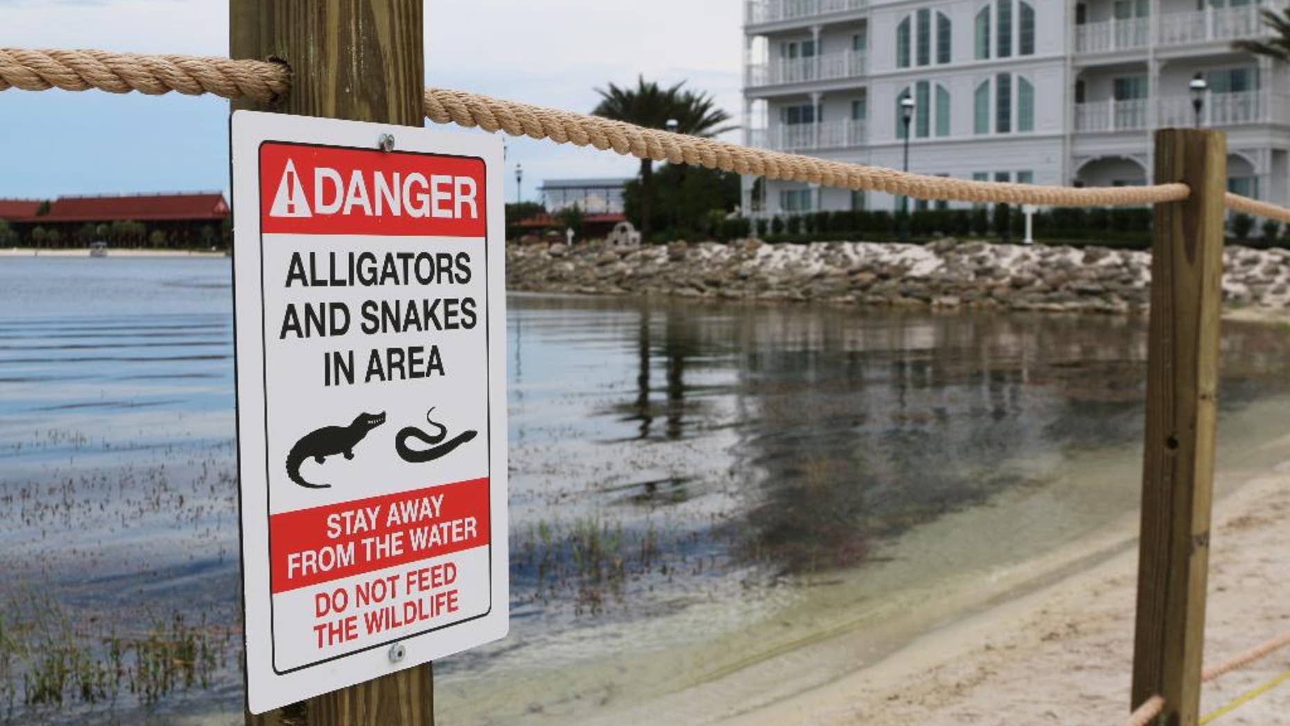 In this Friday, June, 17, 2016 photo released by Walt Disney World Resort, a new sign is seen posted on a beach outside a hotel at a Walt Disney World resort in Lake Buena Vista, Fla. Private family services have been scheduled for a 2-year-old Nebraska boy killed by an alligator at Disney World. Authorities say an alligator pulled Lane Graves into the water last Tuesday, June 14, 2016, despite the frantic efforts of his father. Lane's body was recovered Wednesday. (Walt Disney World Resort via AP)