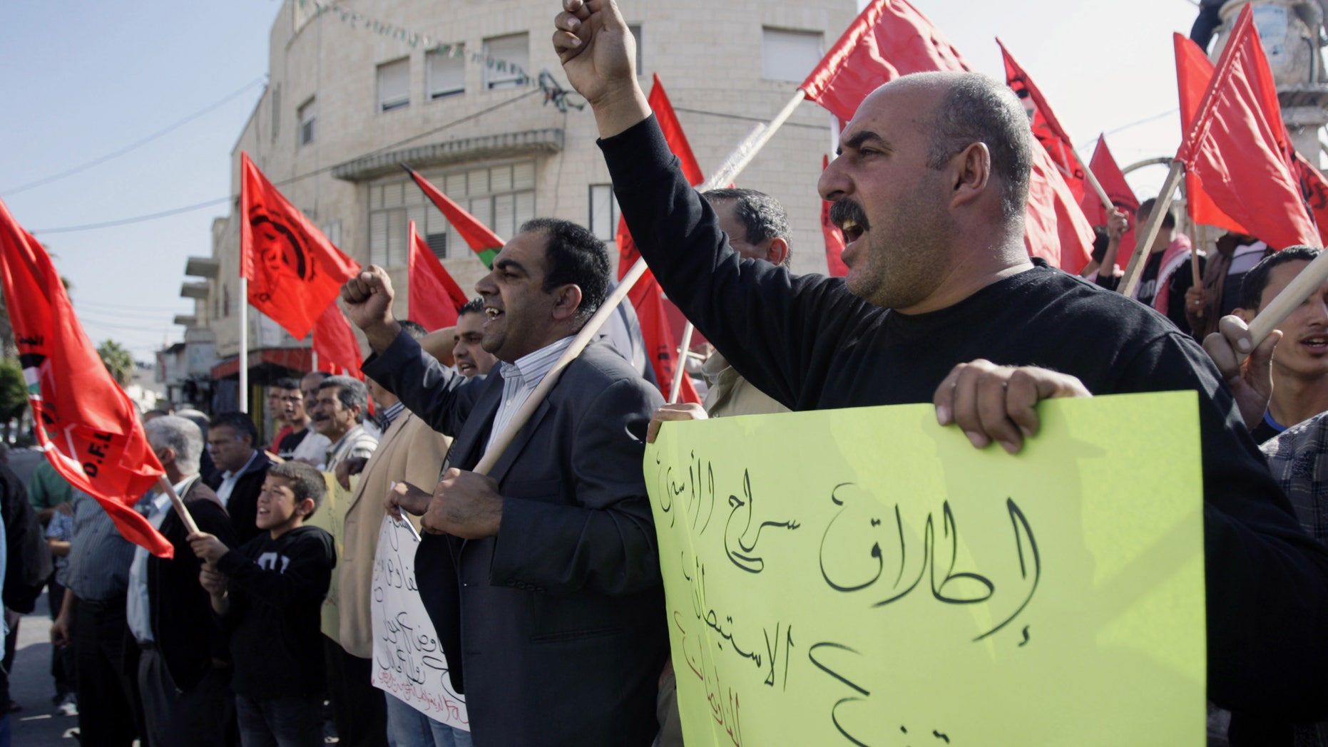 Members of the Democratic Front for the Liberation of Palestine chant slogans against peace negotiations with Israeli, while participating in a demonstration in the West Bank city of Jenin, Thursday, Nov. 21, 2013. The Arabic, front, reads, "Release prisoners and stopping the settlement is the basis to start negotiations." (AP Photo/Mohammed Ballas)