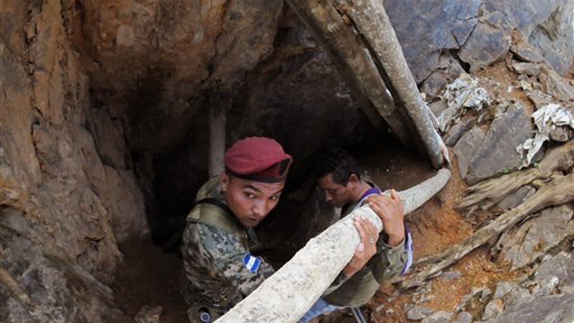 A soldier stands guard at the entrance of a collapsed gold mine where miners are trapped in San Juan Arriba, Choluteca in southern Honduras, Friday, July 4, 2014. Three miners were rescued Friday after spending more than two days trapped following a collapse at a small, wildcat gold mine. Eight others remain missing. (AP Photo/Fernando Antonio)