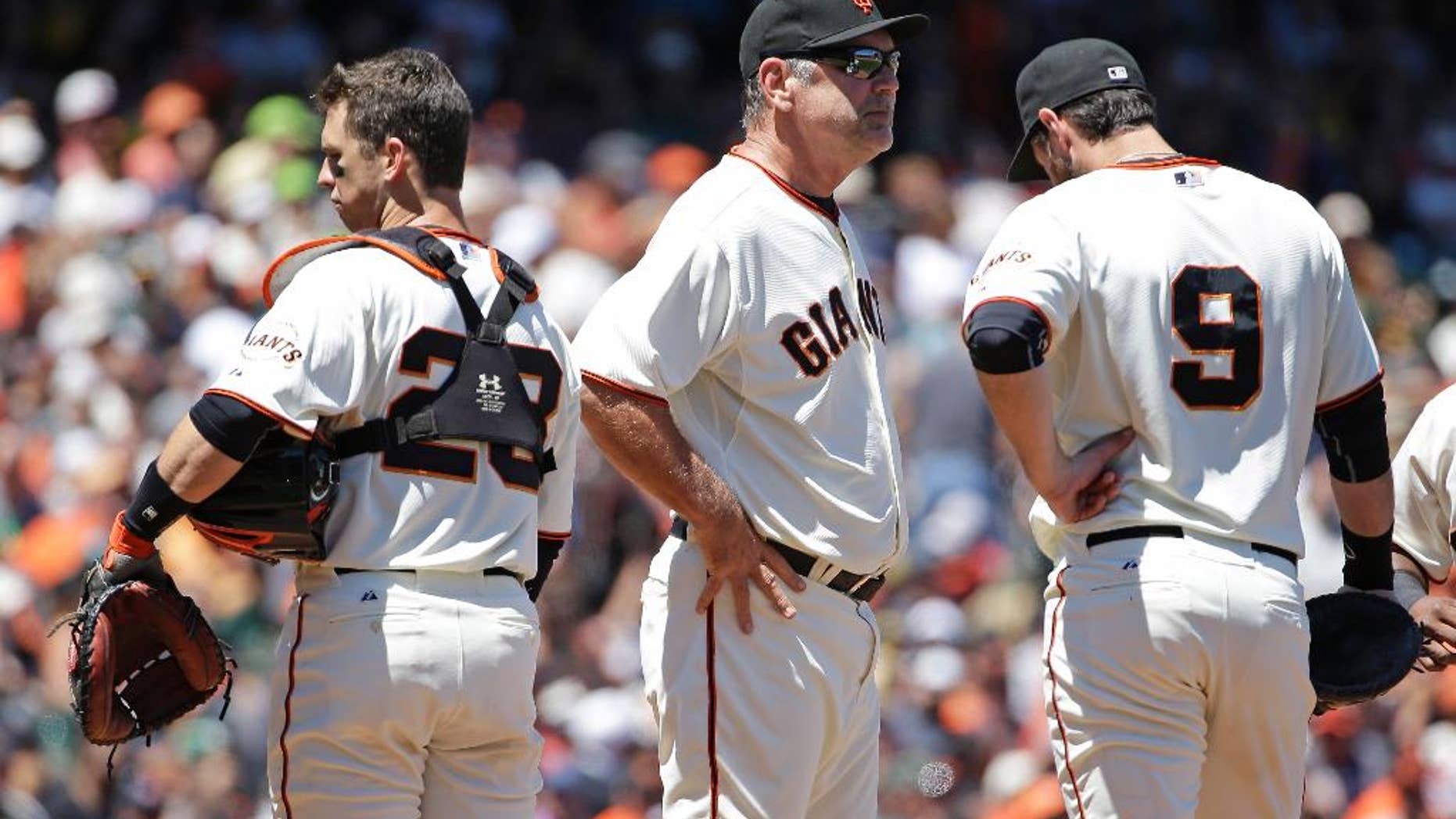 San Francisco Giants manager Bruce Bochy, center, stands on the mound with catcher Buster Posey, left, and first baseman Brandon Belt, right, during a pitching change after the Oakland Athletics scored their sixth run in the sixth inning of their interleague baseball game Thursday, July 10, 2014, in San Francisco. Bochy was relieving relief pitcher Javier Lopez. (AP Photo/Eric Risberg)