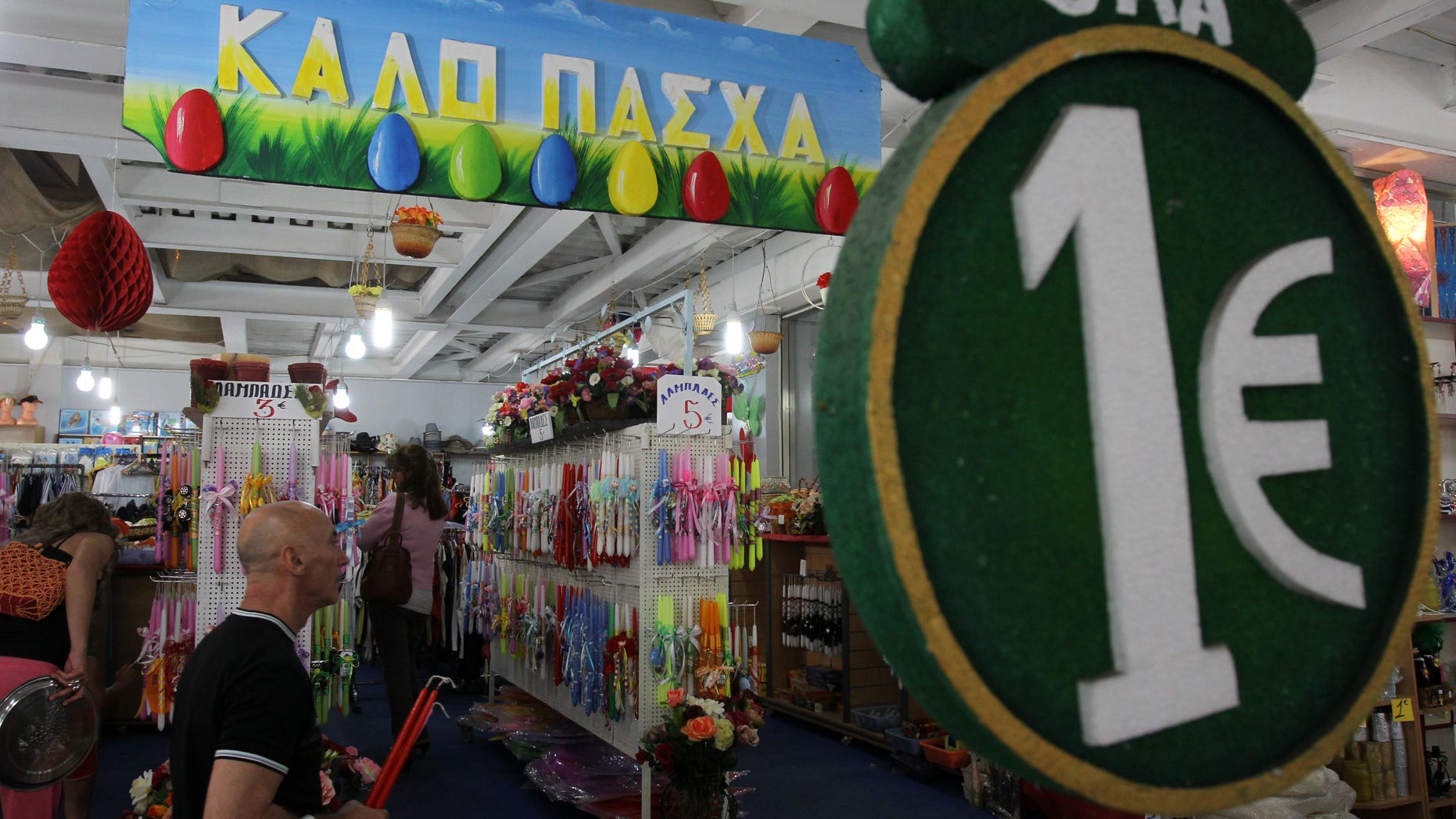 A one-euro sign and a banner reading "Happy Easter" are displayed at a discount store selling candles and other items at the start of Orthodox Holy Week, in Athens, Monday, April 29, 2013. Orthodox Christians around the world celebrate Easter on Sunday, May 5. Retailers and travel agents booking domestic trips are expecting slower sales over the Easter holidays, with a continued recession expected to see Greece's crisis-hit economy contract a further 4.25 percent this year. (AP Photo/Thanassis Stavrakis)