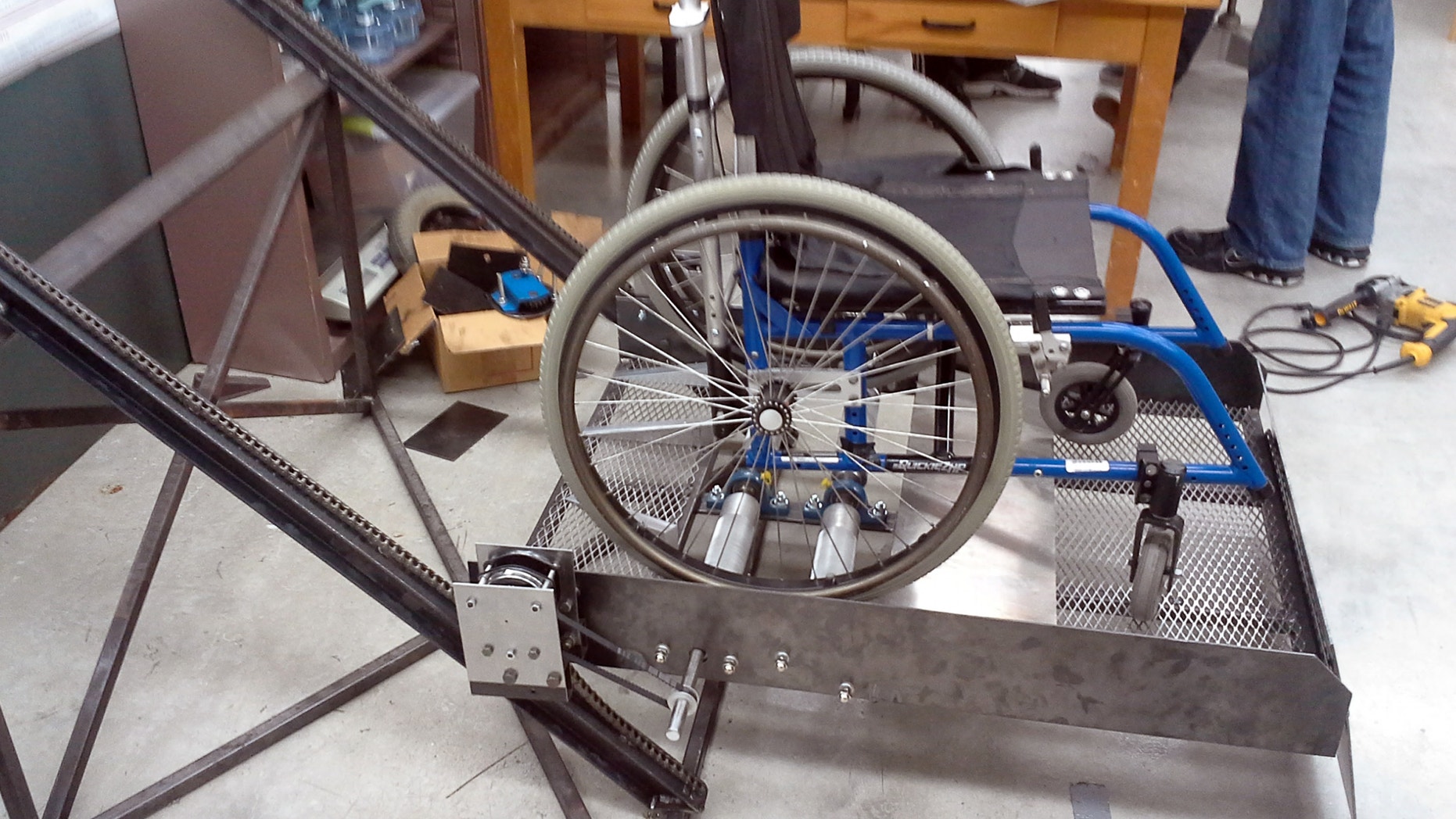 This April 2013 photo provided by Joe Kloptic shows a prototype called the Funicular in Madison, Wis. A University of Wisconsin-Madison engineering professor, students and others helped come up with it after getting in touch with a local elementary school that wasn't handicapped accessible. The platform uses rollers and a modified chain hoist that allows the wheelchair users to use their own energy to move and down up a stairways. (AP Photo/Joe Kloptic)